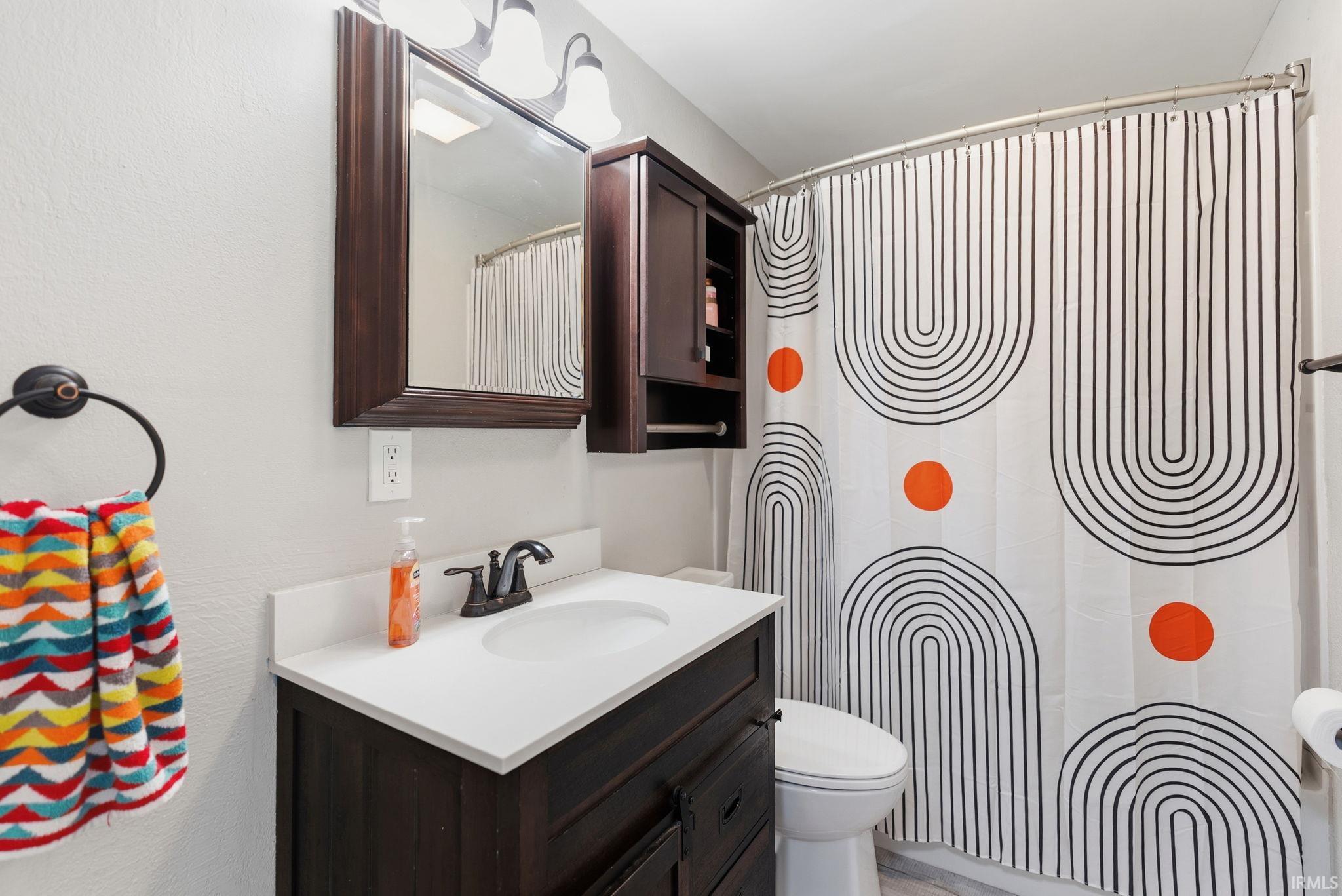 Bathroom vanity with dark wood-finish cabinetry, a white countertop, and an integrated sink basin