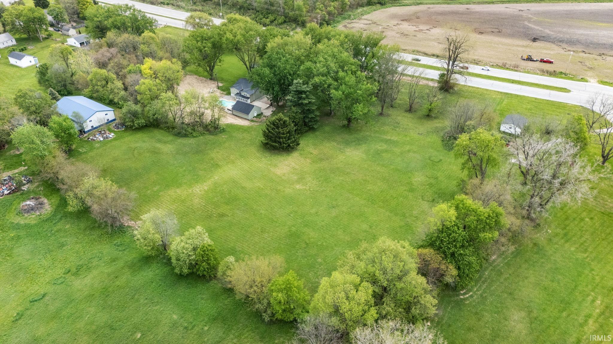 Expansive green acreage featuring mature trees and a substantial outbuilding with a blue metal roof
