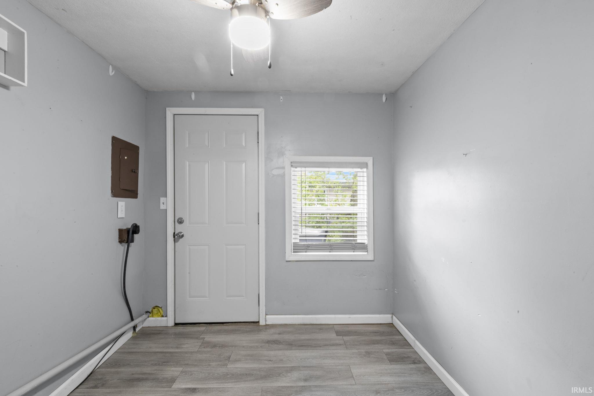 Interior space featuring wood-finish flooring, light gray wall paint, and a white paneled door