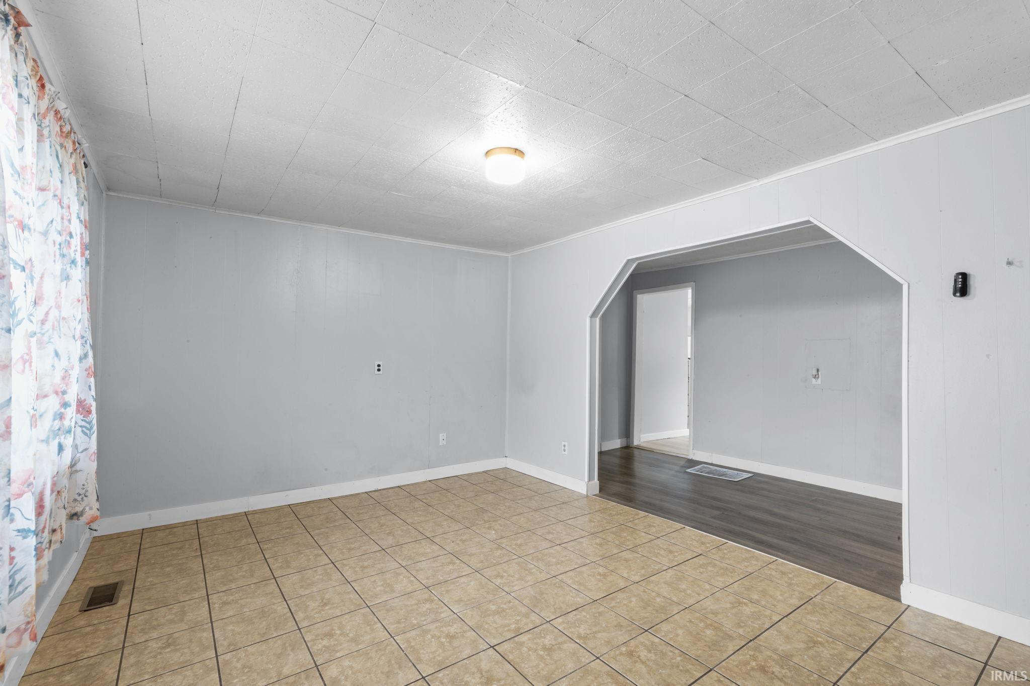 Interior living area featuring light-toned tile flooring, light gray walls, and white ceiling panels