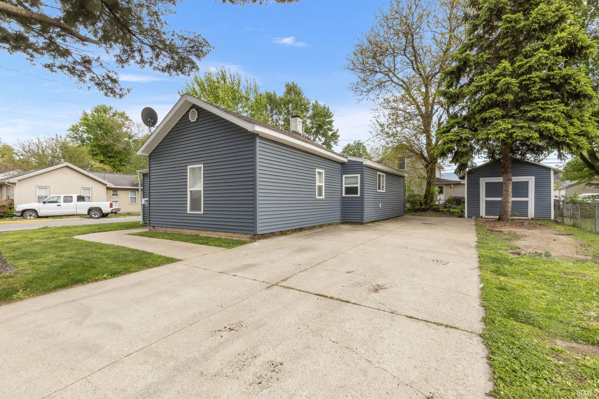 Exterior featuring blue vinyl siding, white trim, and a gabled roofline