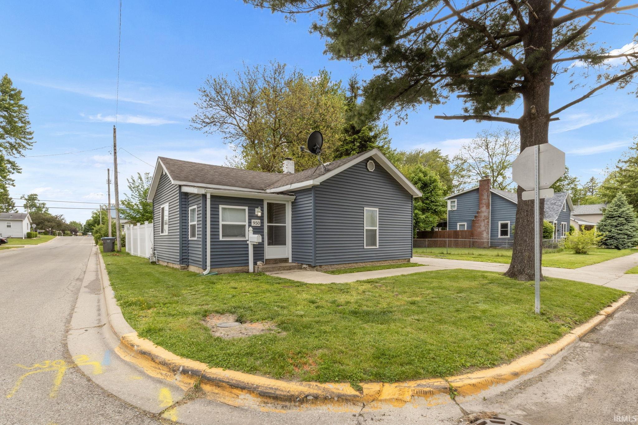 Corner lot property featuring blue horizontal siding, white trim windows, a front entry, and a white picket fence