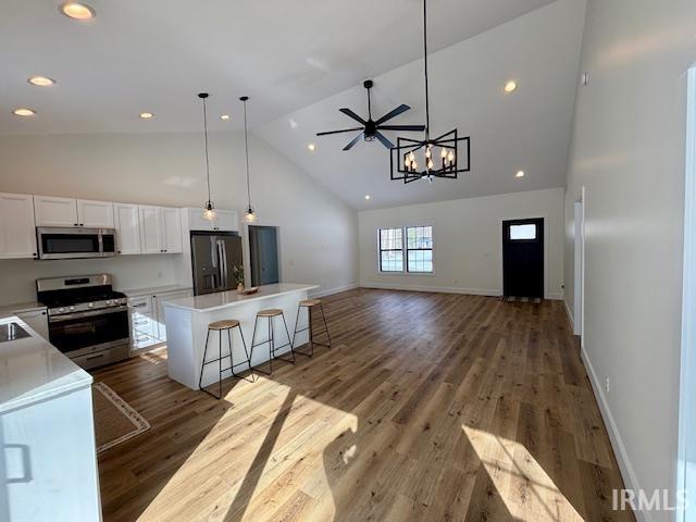 Vaulted ceilings featuring recessed lighting, a contemporary chandelier, and a ceiling fan