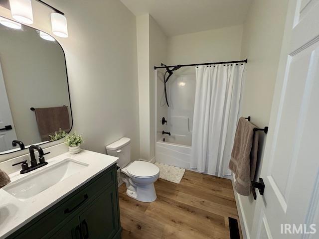 Bathroom featuring a dark green vanity with a white countertop and undermount sink, black hardware, wood-finish flooring, and a white tub/shower combination with black fixtures