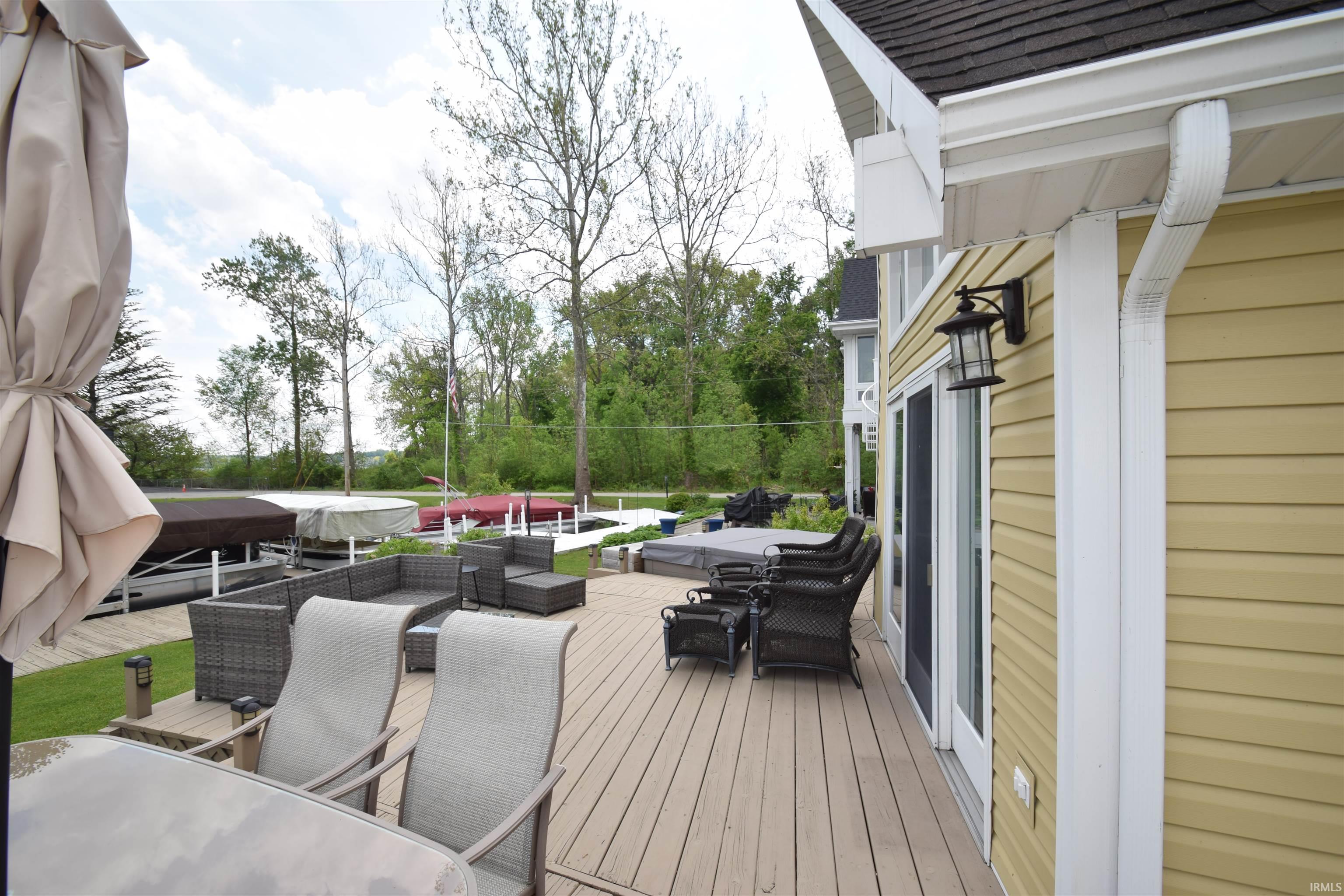 Expansive outdoor deck featuring wood-finish flooring, direct access via sliding glass doors, and a built-in hot tub