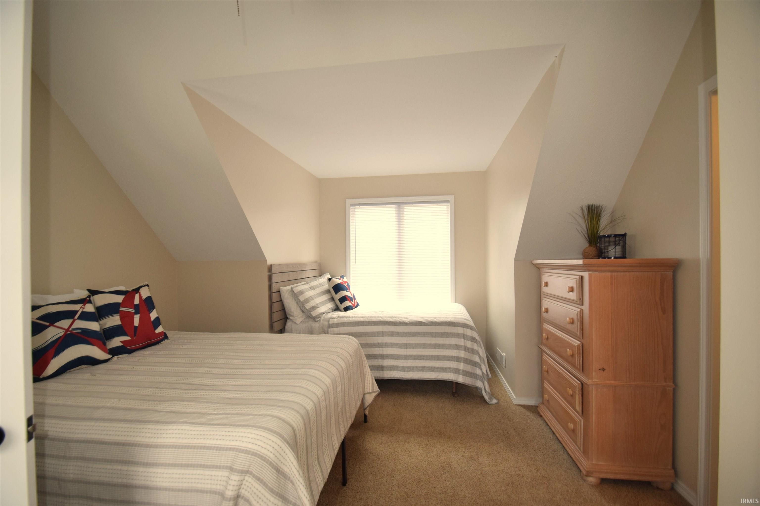 Room featuring a window with natural light, sloped ceilings, light-colored walls, and carpet flooring