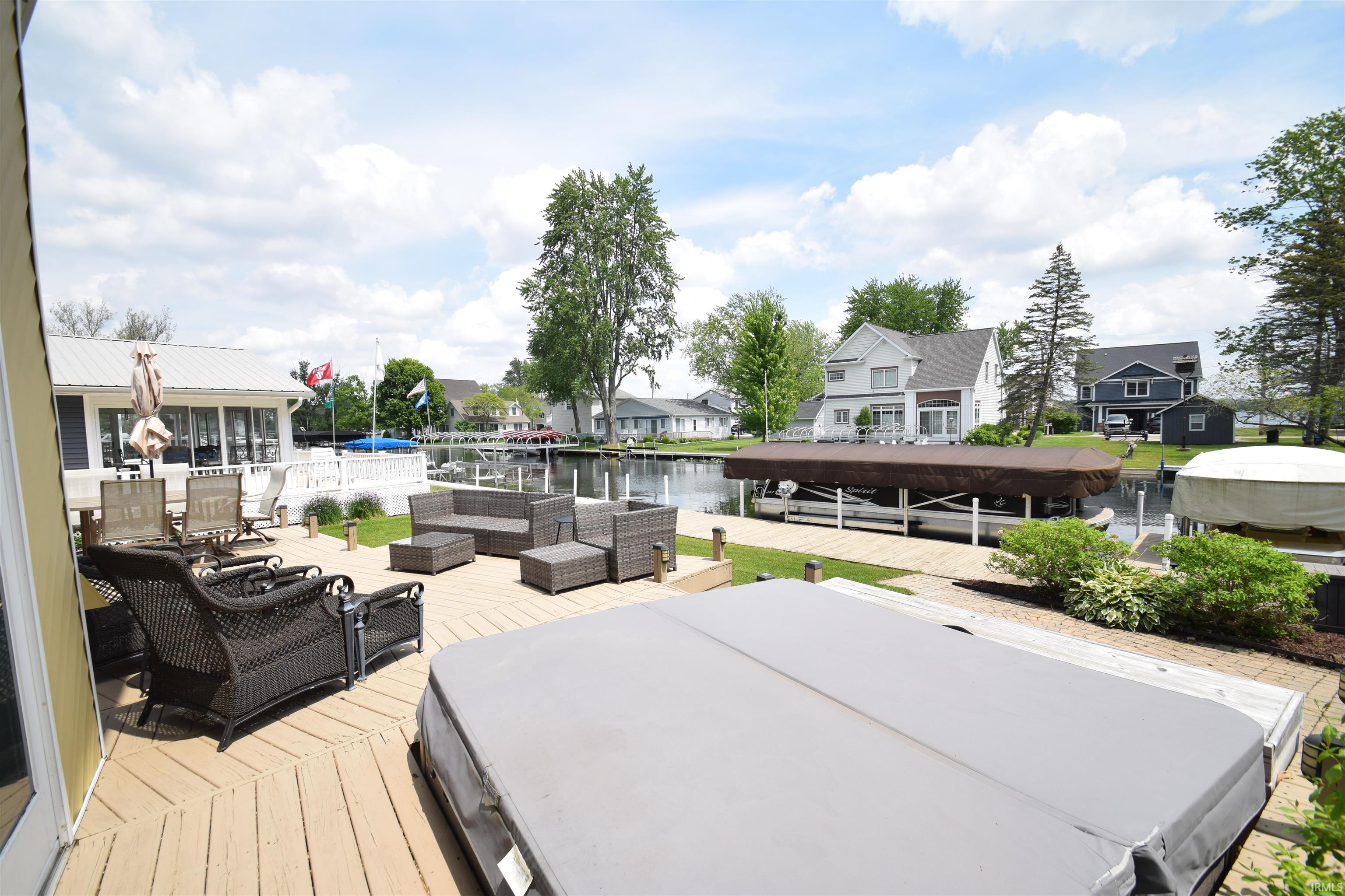 Spacious outdoor deck with a hot tub, stone paver patio, and direct waterfront access featuring a boat lift and additional dock space