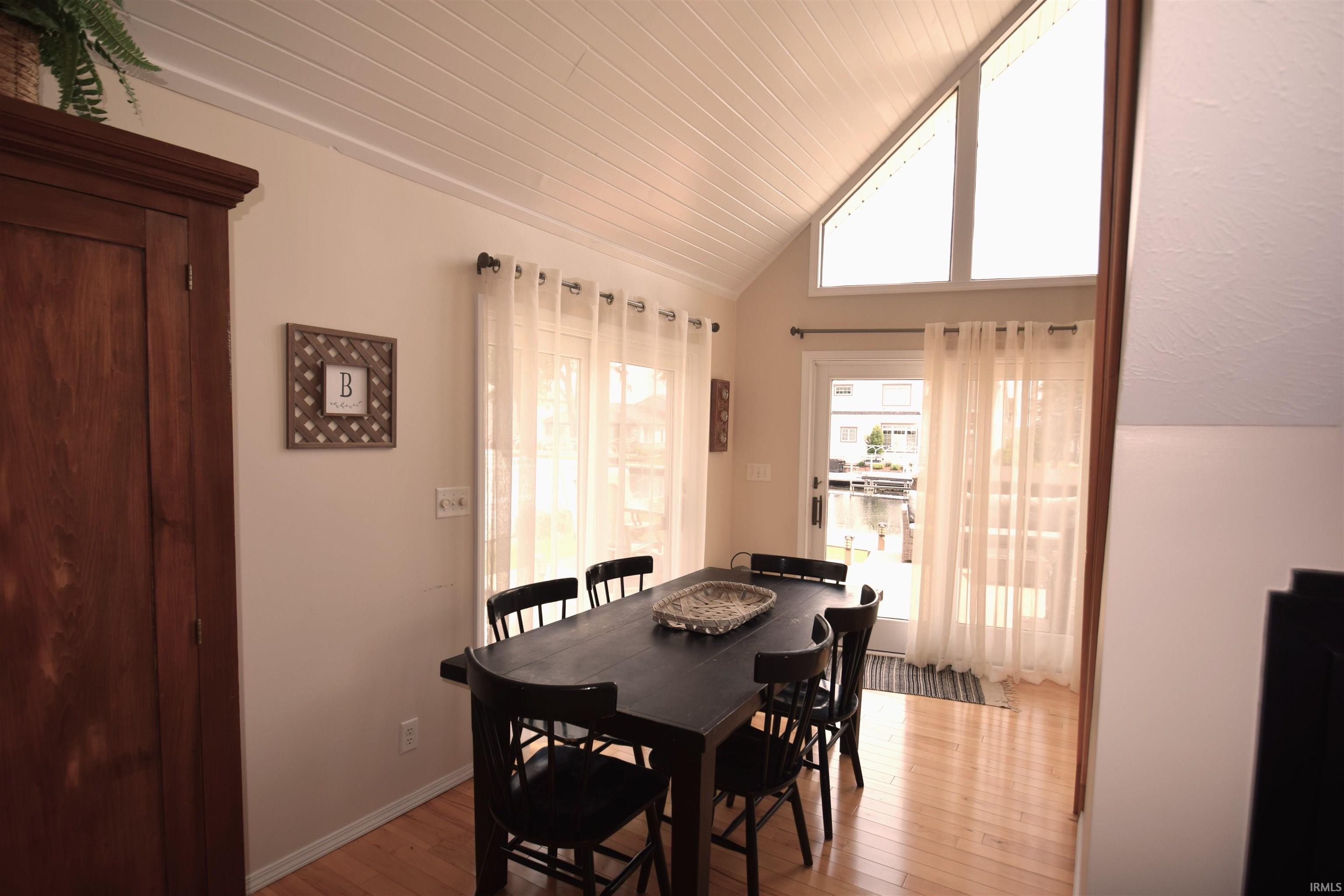 Vaulted planked ceiling above a dining area with wood-finish flooring