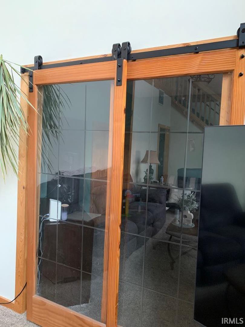 Wood-frame barn doors with clear glass panes and black metal hardware