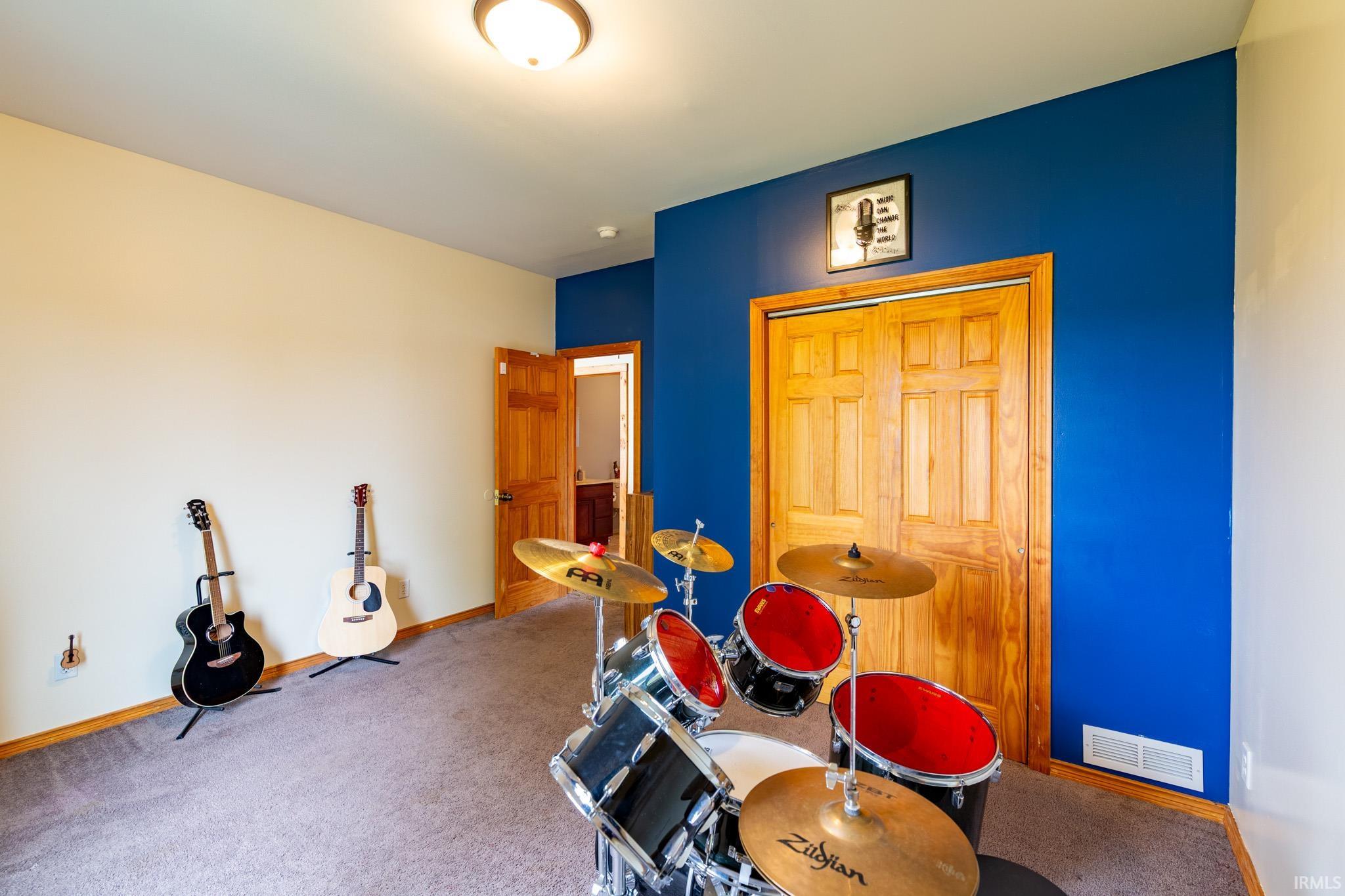 Carpeted room with a blue accent wall and natural wood bi-fold closet doors