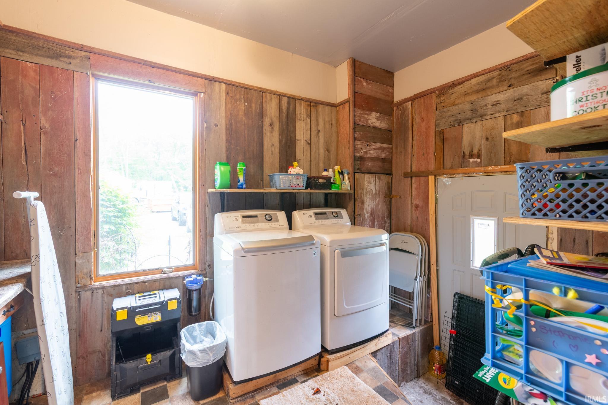 Utility room featuring wood-finish wall paneling, a large window, built-in shelving, and checkered floor tiling
