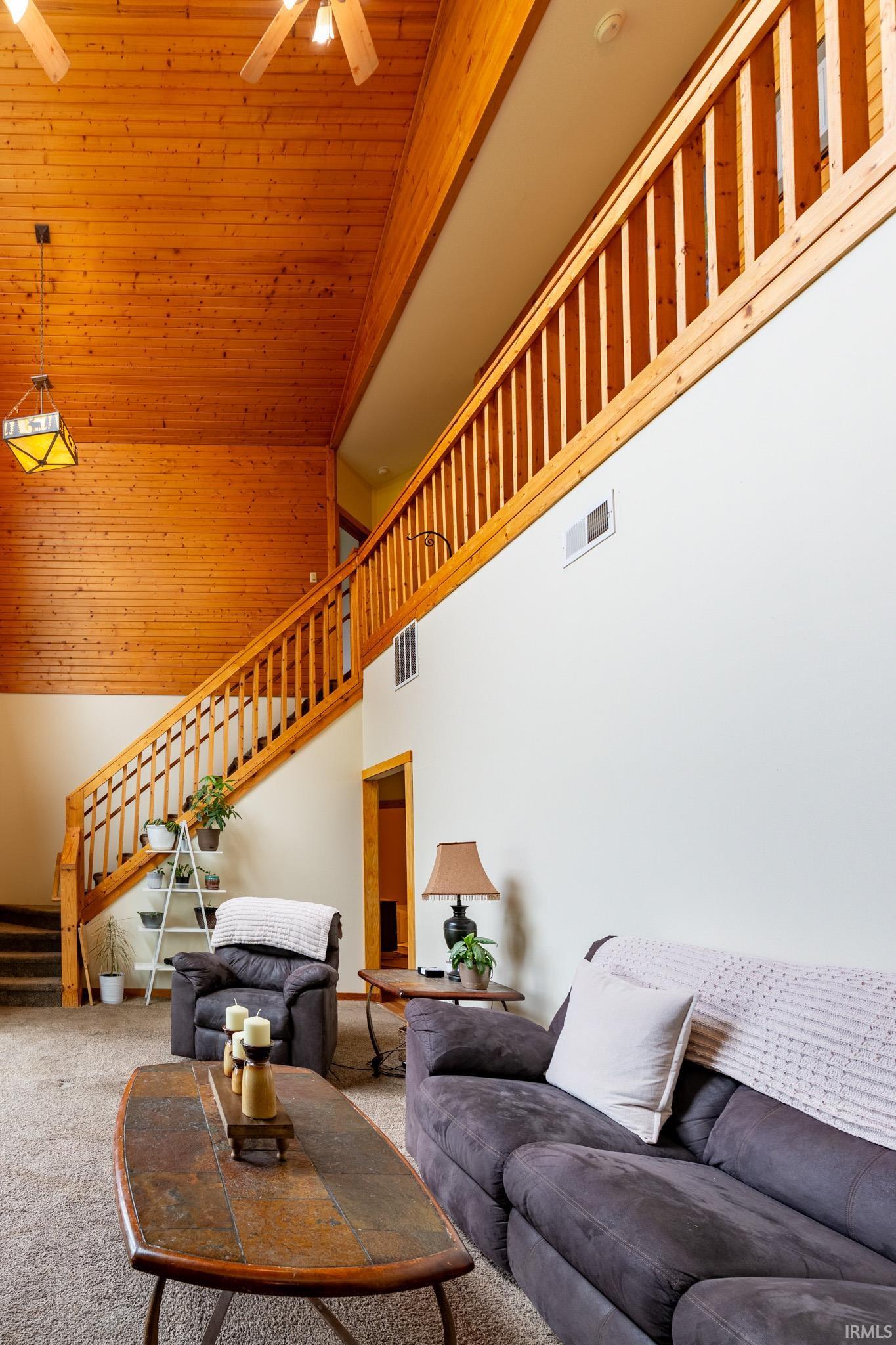 Vaulted ceiling with wood-finish paneling, exposed wood-finish beams, and ceiling fans