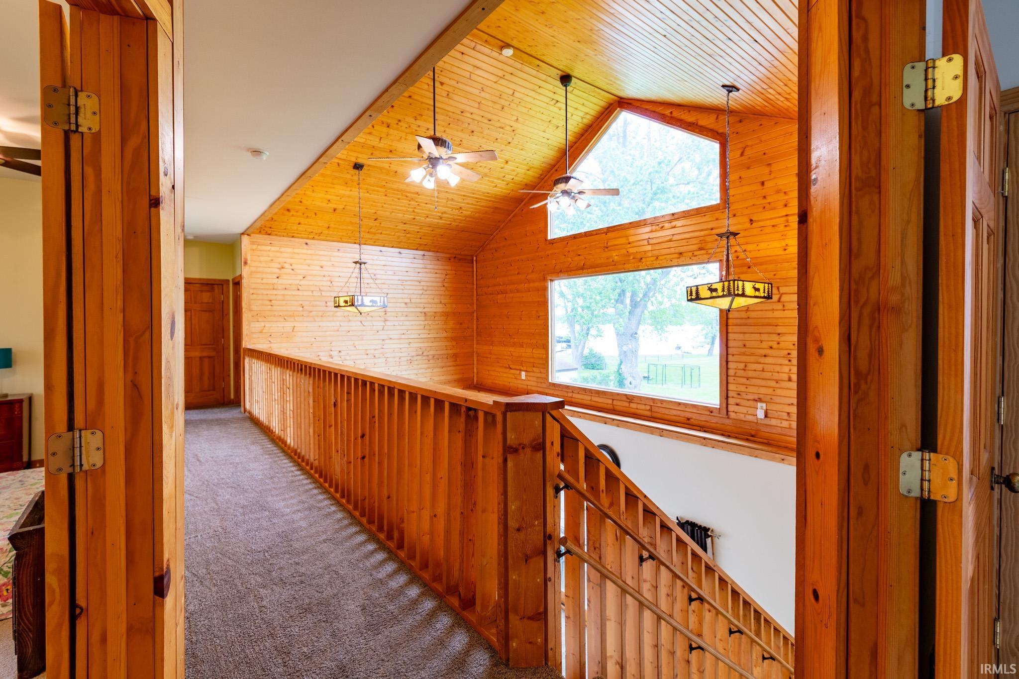 Vaulted wood-paneled ceiling with exposed beams, illuminated by multiple ceiling fans and hanging fixtures