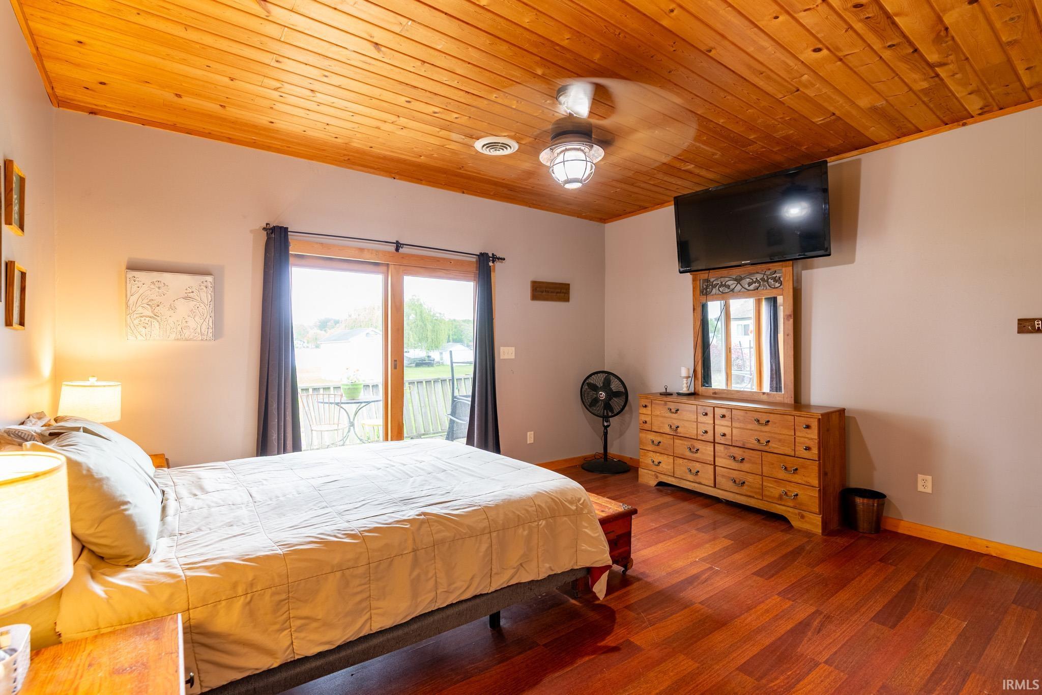 Room featuring wood-finish flooring, a wood-paneled ceiling, and a ceiling fan with integrated lighting