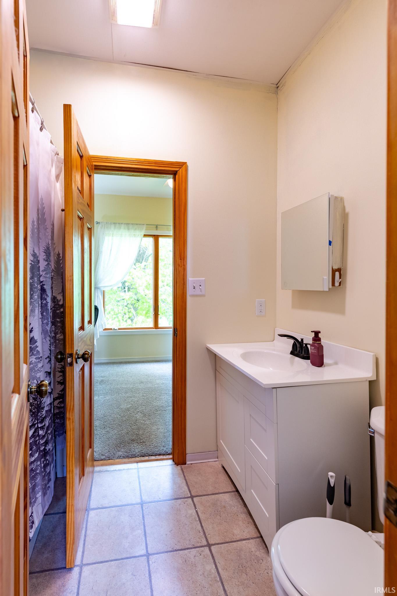 Bathroom featuring a white vanity with an integrated sink, black faucet, and tiled flooring