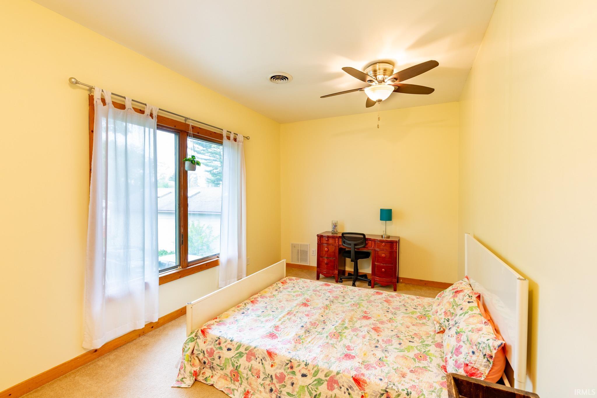 Bright room featuring a ceiling fan with integrated lighting, wood-trimmed window, and light-toned walls