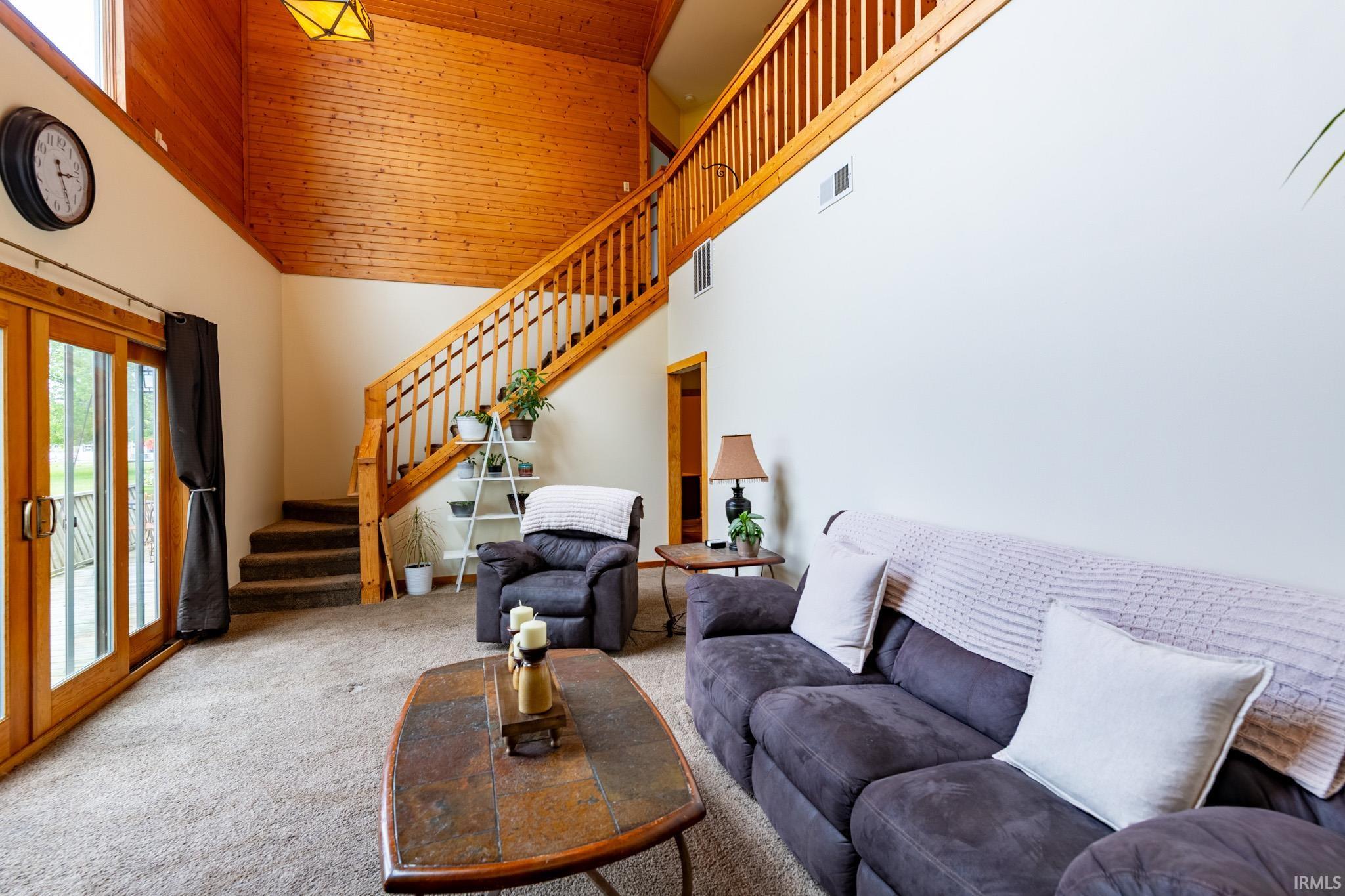 Vaulted wood-paneled ceiling with an exposed beam, light wood staircase with a baluster railing, and a second-story overlook