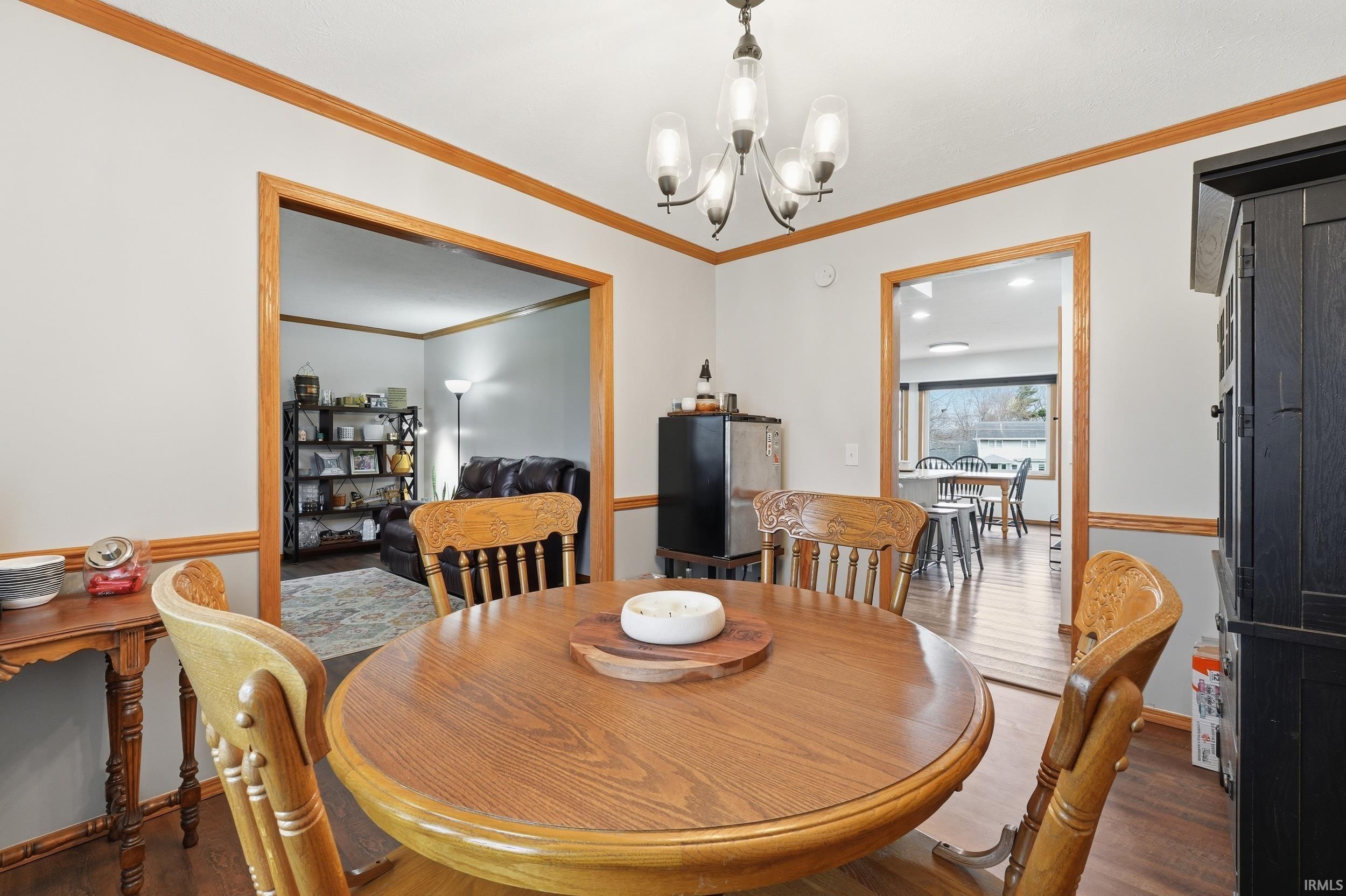 Dining room with wood finished floors, suspended lighting, and ornamental molding