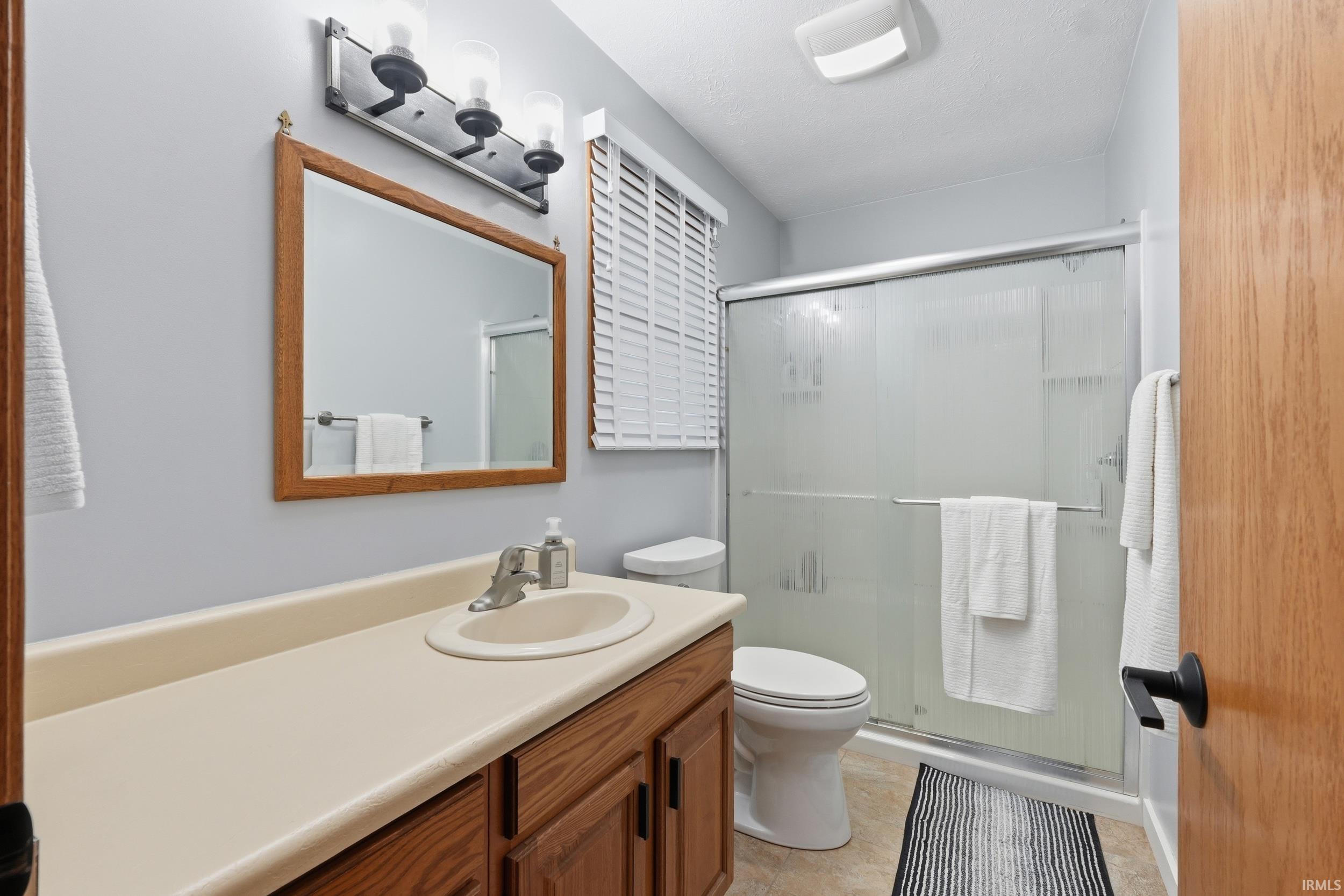 Bathroom with a stall shower, vanity, and light tile patterned flooring