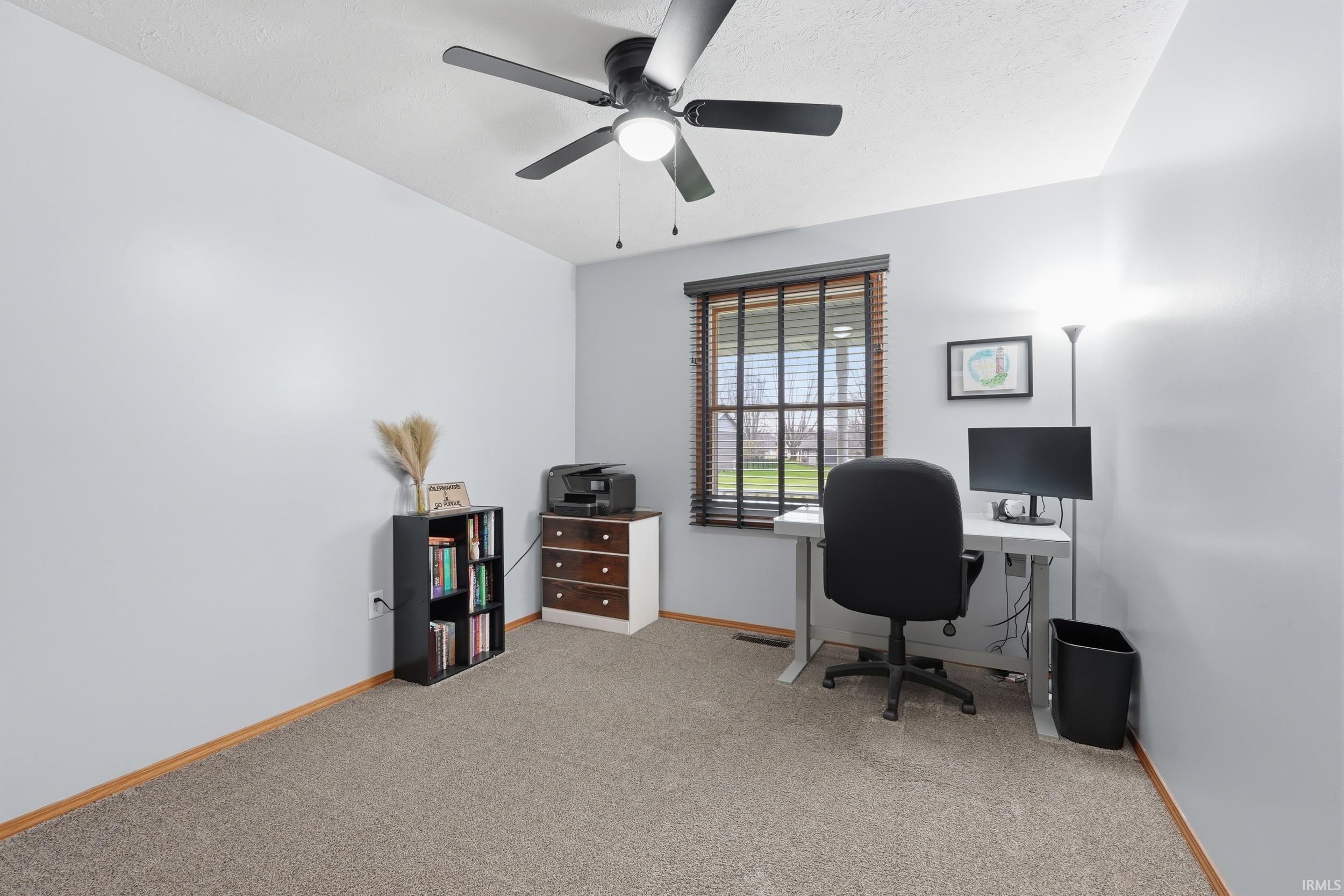 Office with light colored carpet and ceiling fan