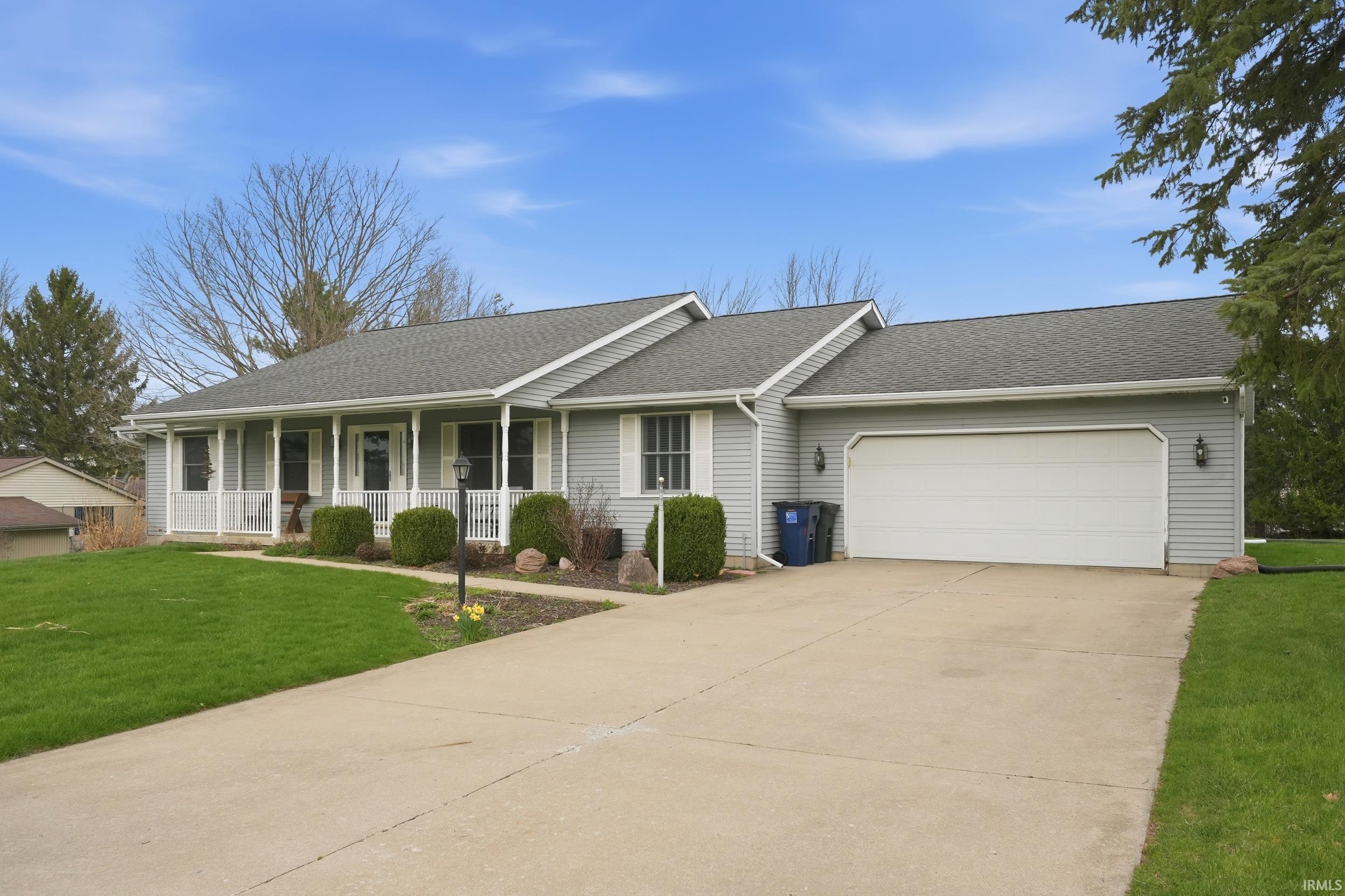 Single story home with a porch, a front yard, roof with shingles, a garage, and driveway