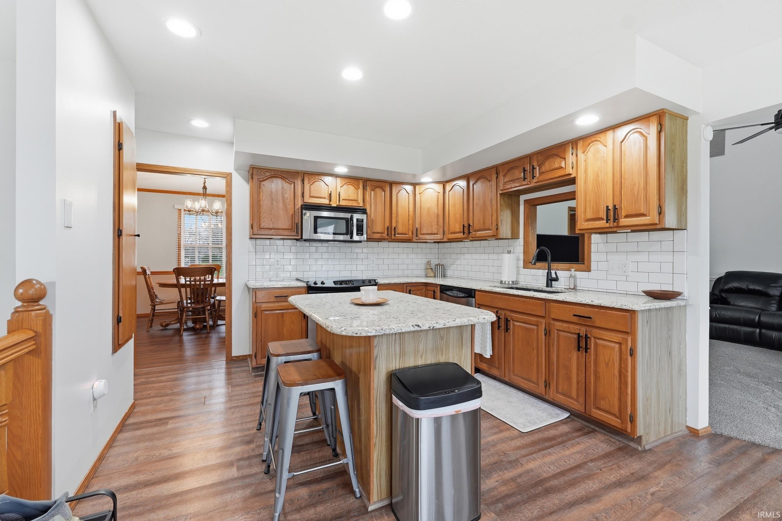 Kitchen with a kitchen breakfast bar, light stone counters, dark wood-type flooring, and a kitchen island