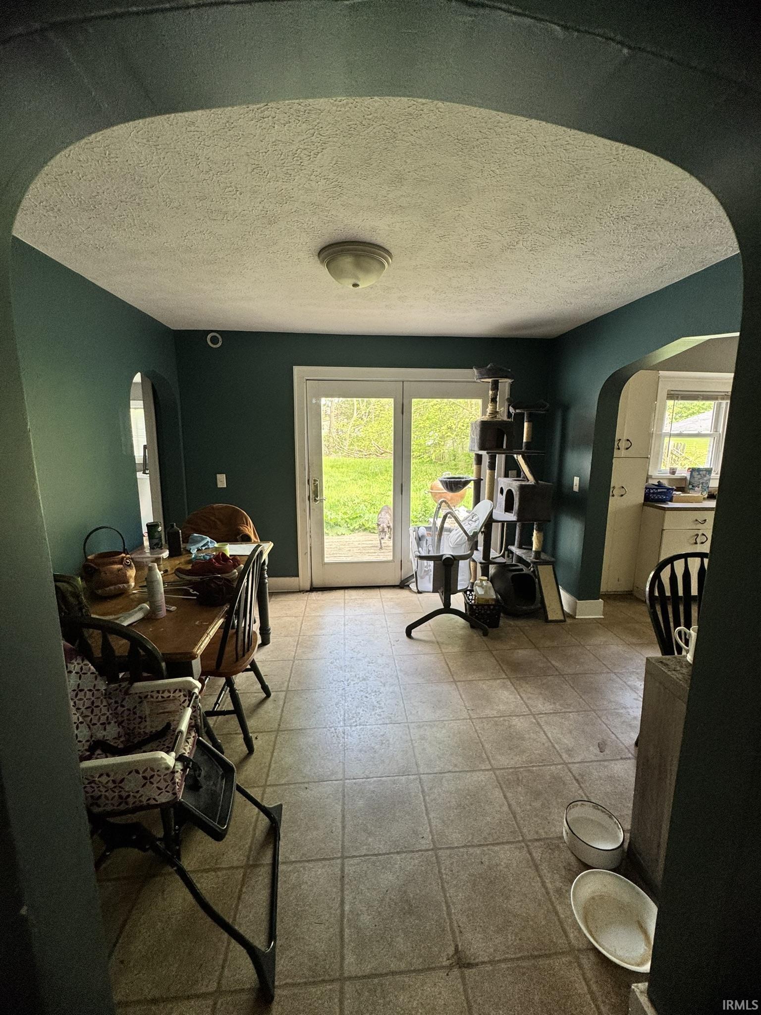 Dining area featuring French doors opening to exterior, overhead flush-mount lighting, and neutral-toned tile flooring