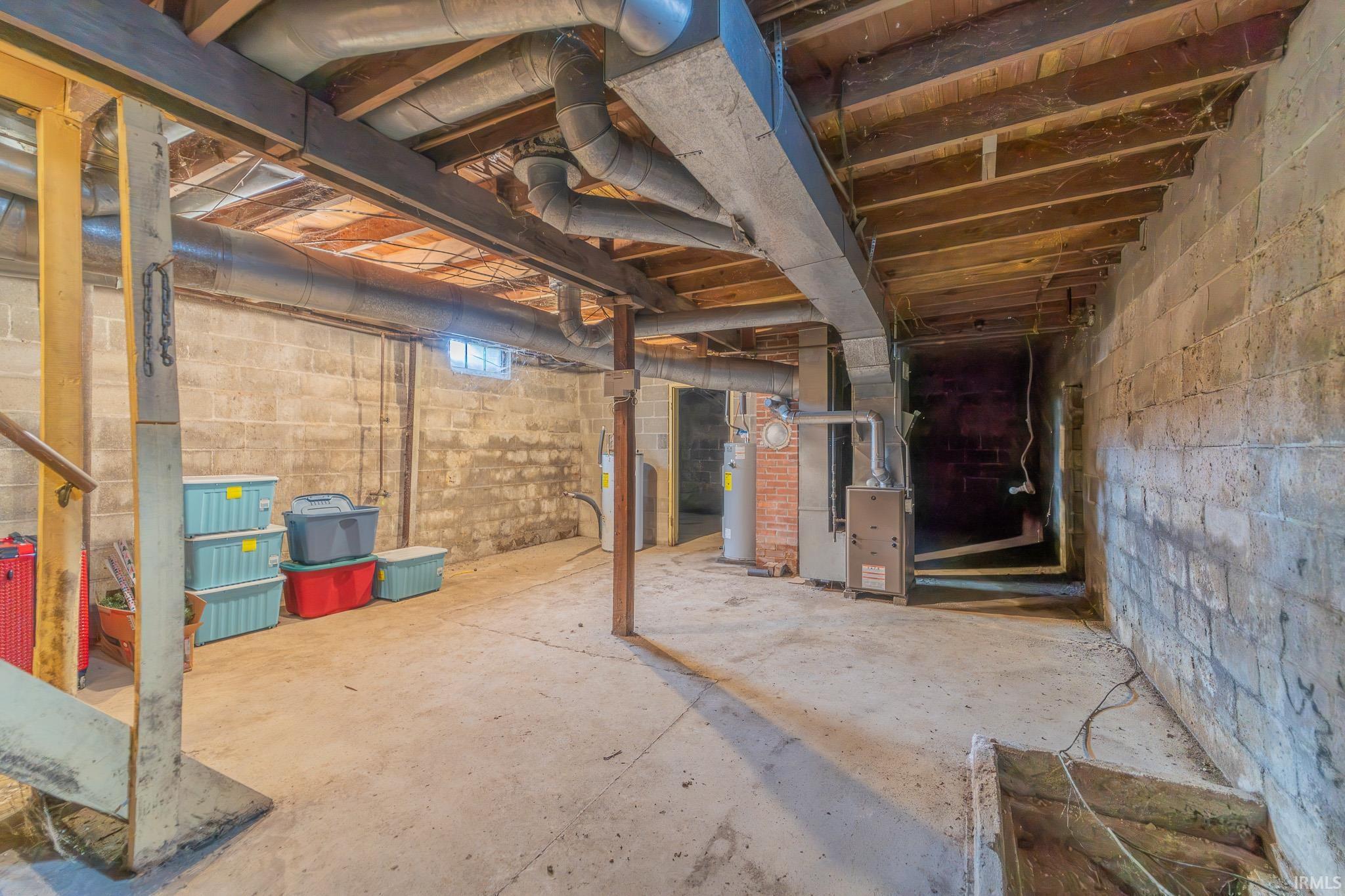 Unfinished basement with concrete slab flooring and concrete block walls