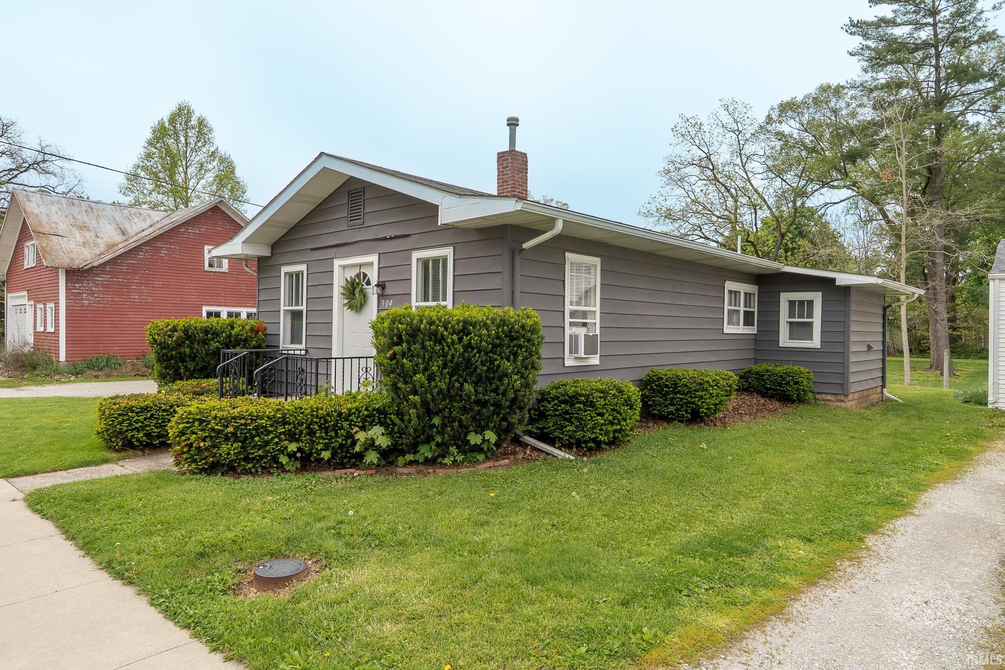 Gray siding exterior with white trim, a covered porch, and a brick chimney