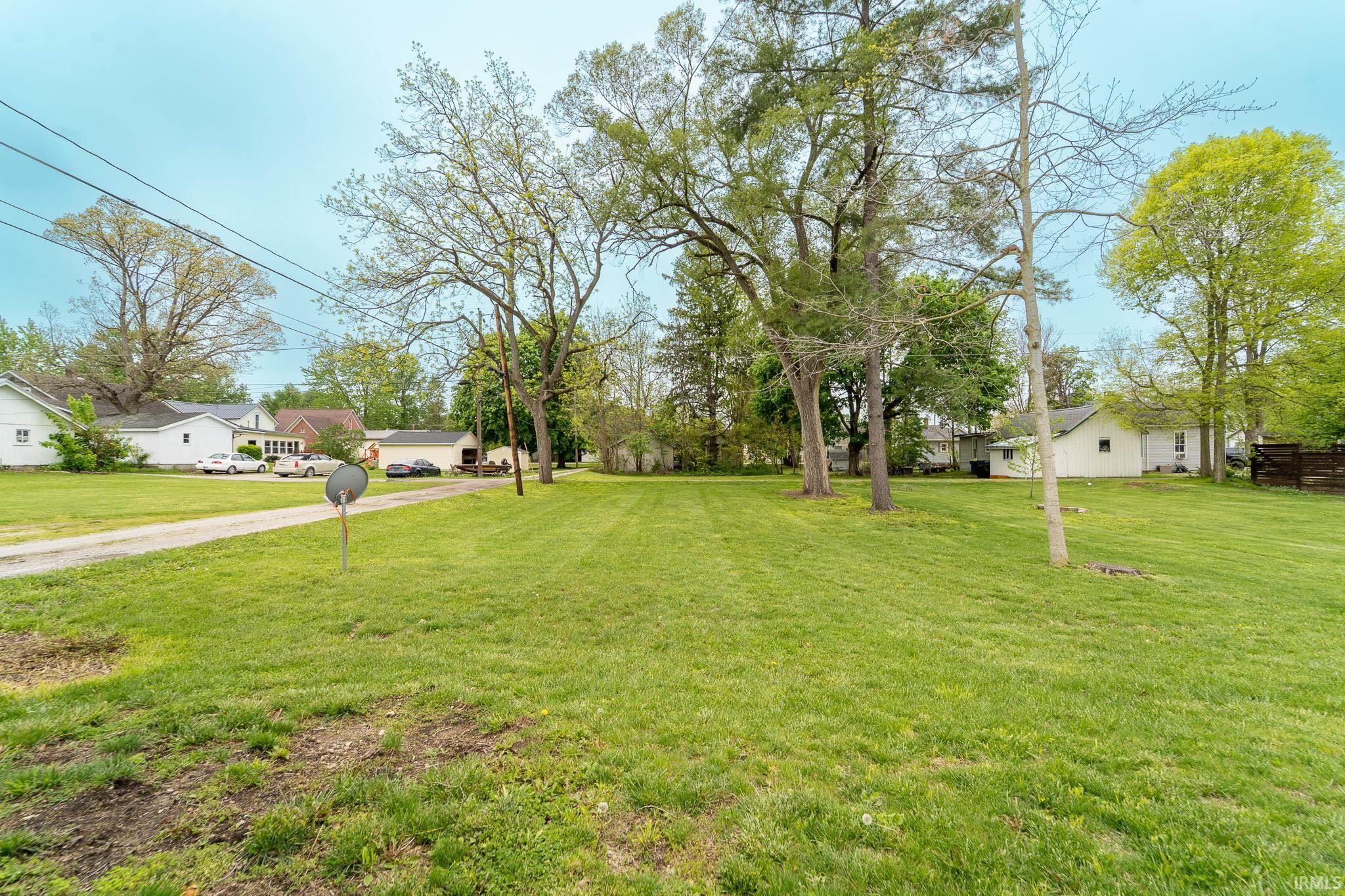 Expansive grassy lot with mature trees providing natural shading