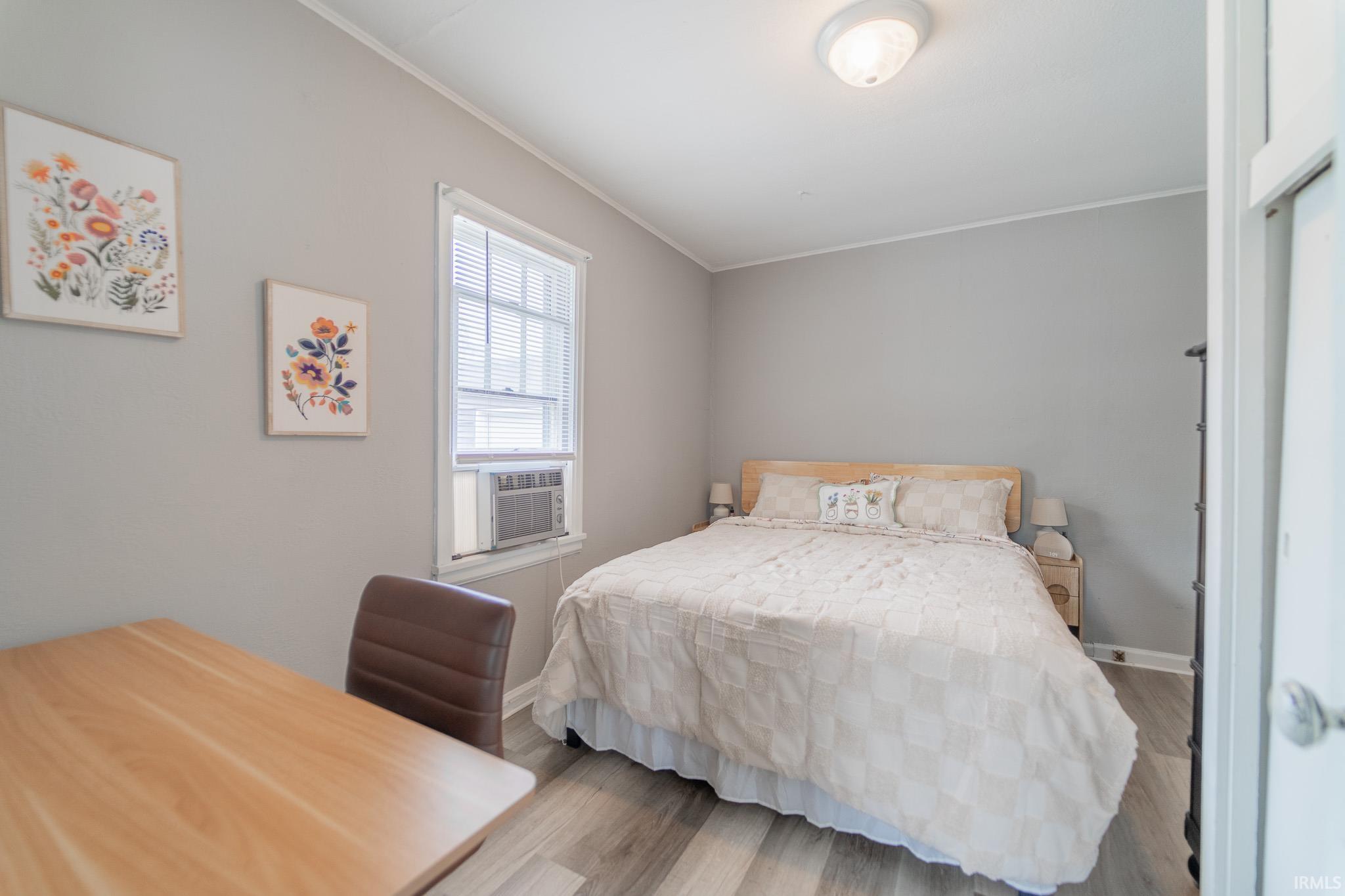 Bedroom featuring wood-finish flooring, light gray wall paint, and a single window with blinds