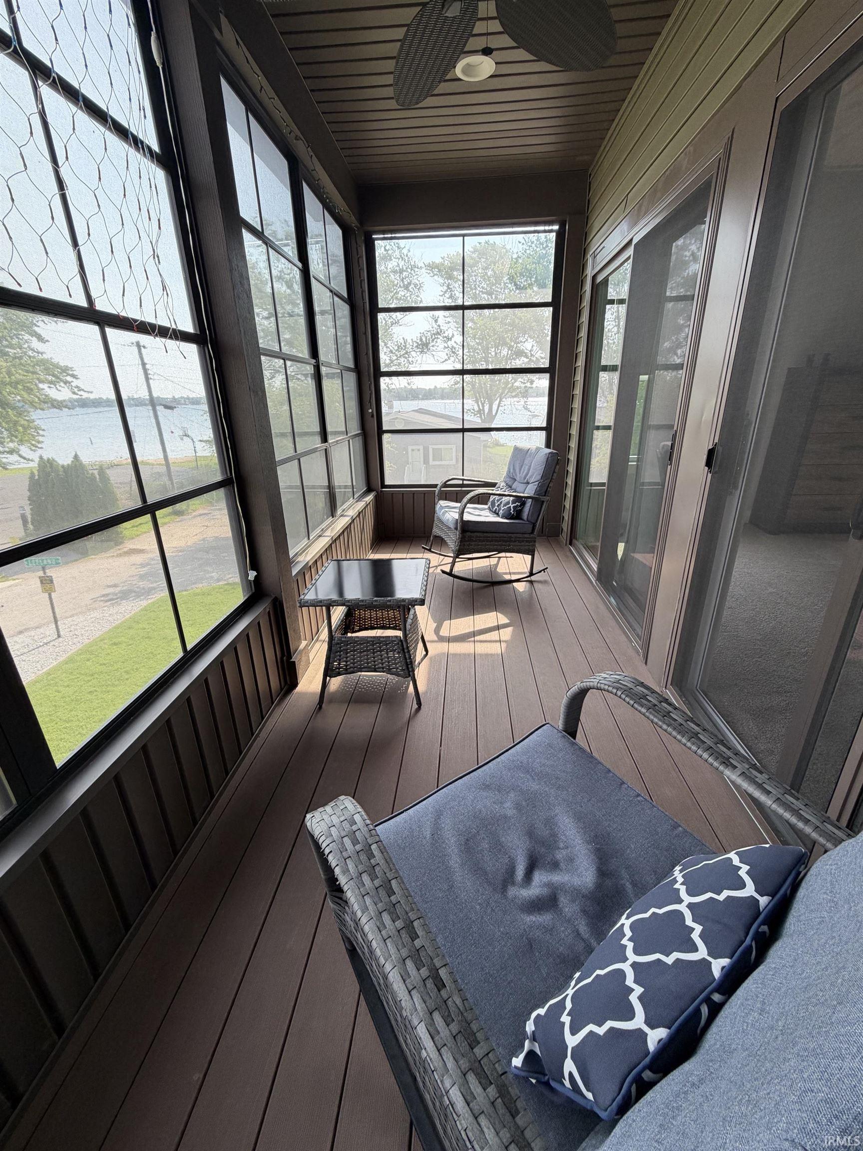Screened-in porch featuring a wood-finish floor and ceiling with an attached ceiling fan