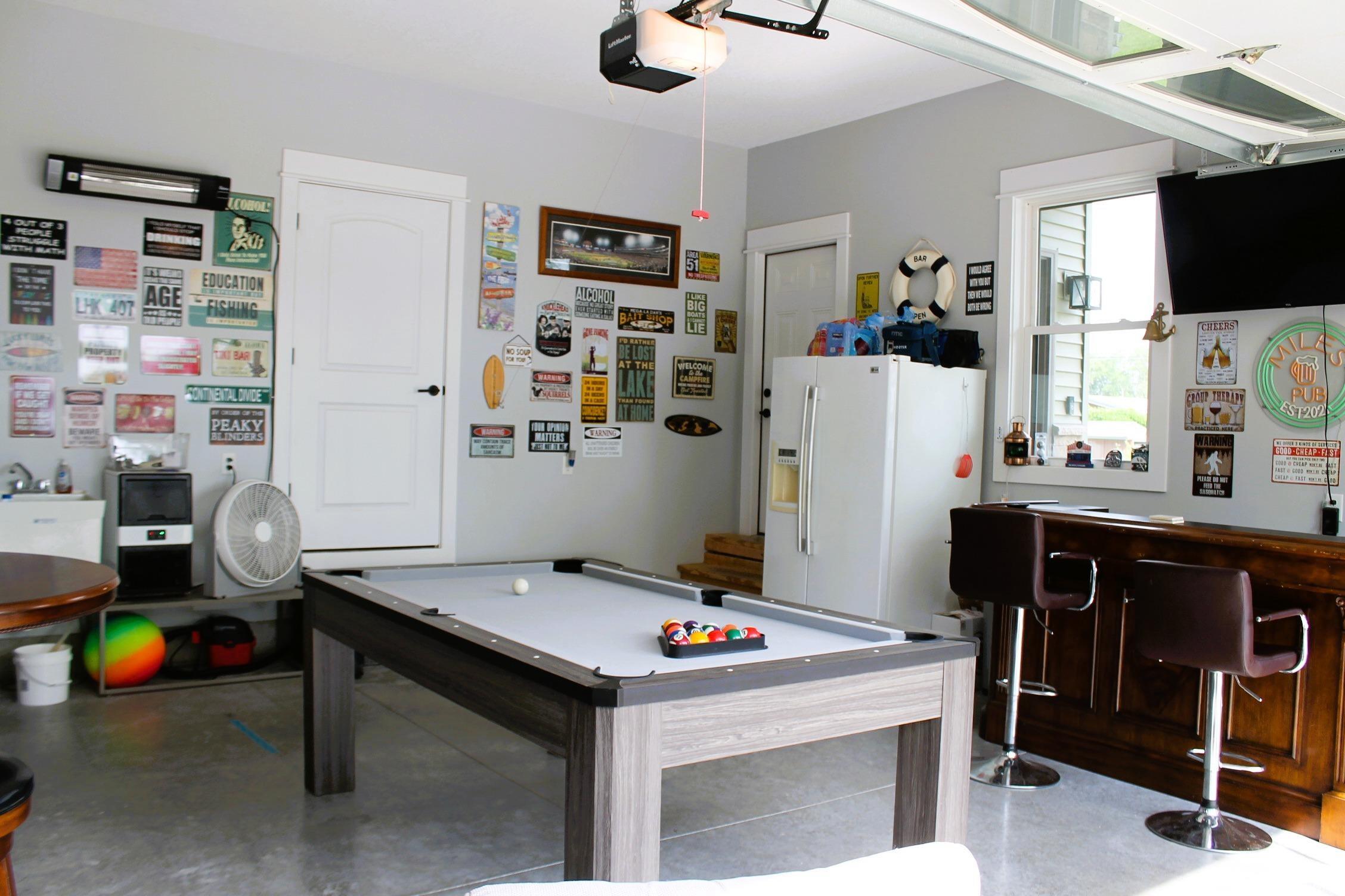 Garage space featuring concrete flooring, a paneled wooden bar with stools, and a wall-mounted television
