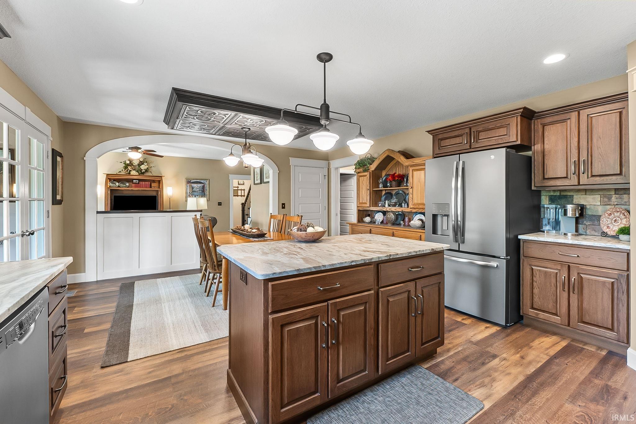 Kitchen featuring a central island with a stone countertop, wood-finish flooring, recessed lighting, and dark wood cabinetry
