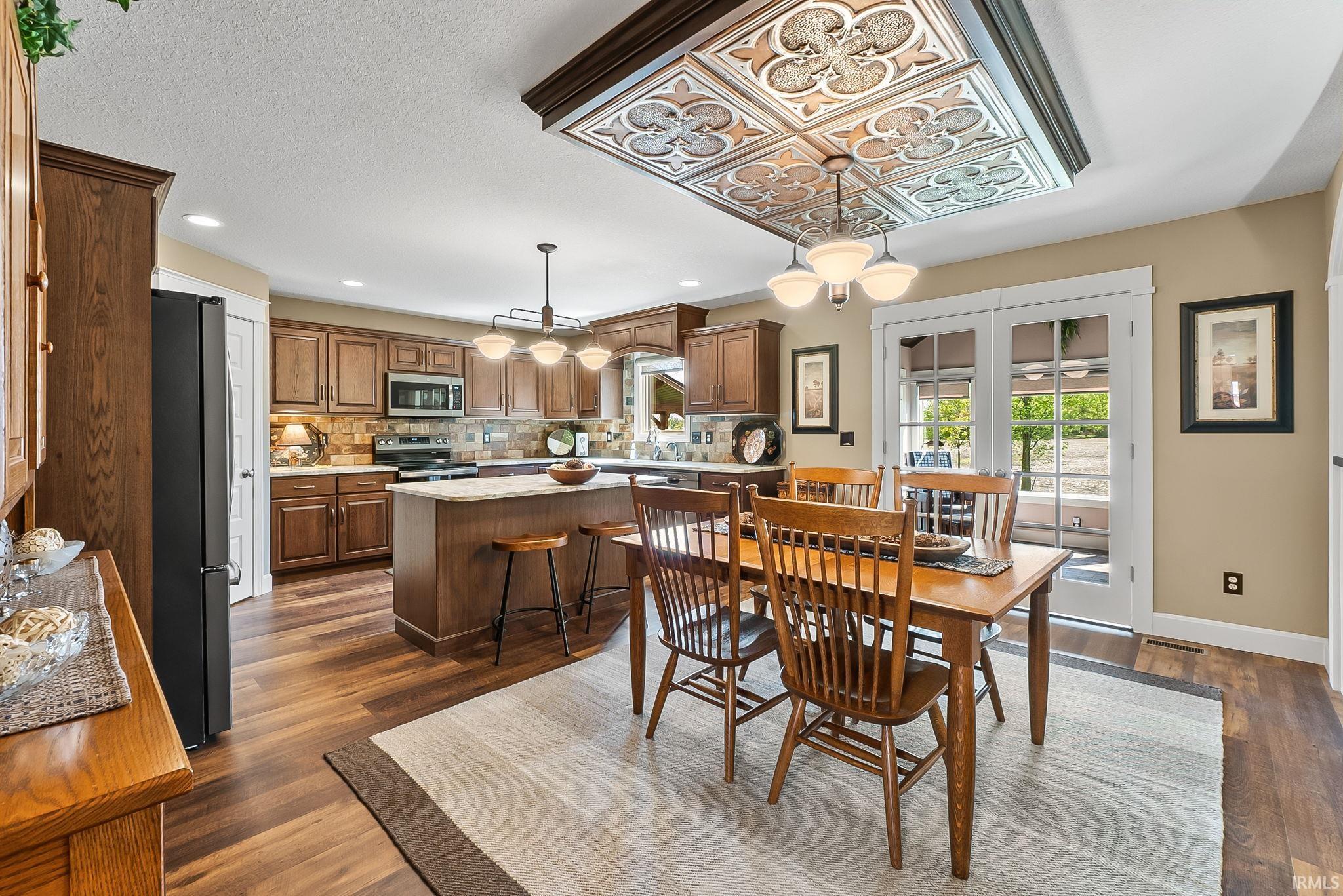 Kitchen and dining area featuring wood-finish flooring, recessed lighting, and a decorative coffered ceiling detail with an integrated light fixture