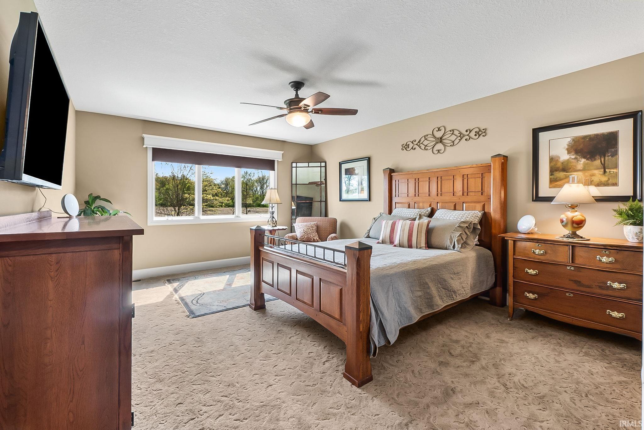 Carpeted room featuring a large window with white trim, a ceiling fan with integrated lighting, and neutral-toned walls