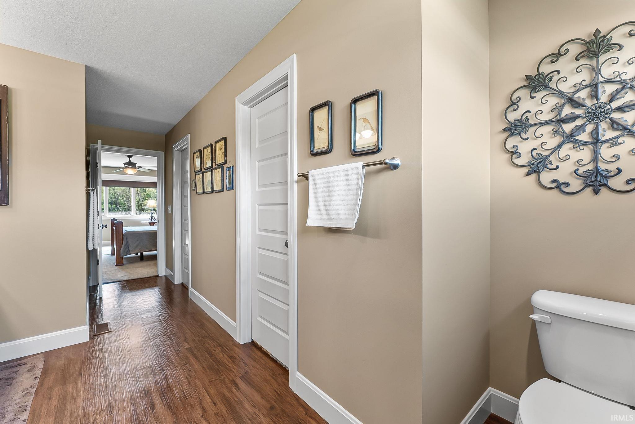 Hallway featuring wood-finish flooring, neutral wall paint, white baseboards, and white paneled doors