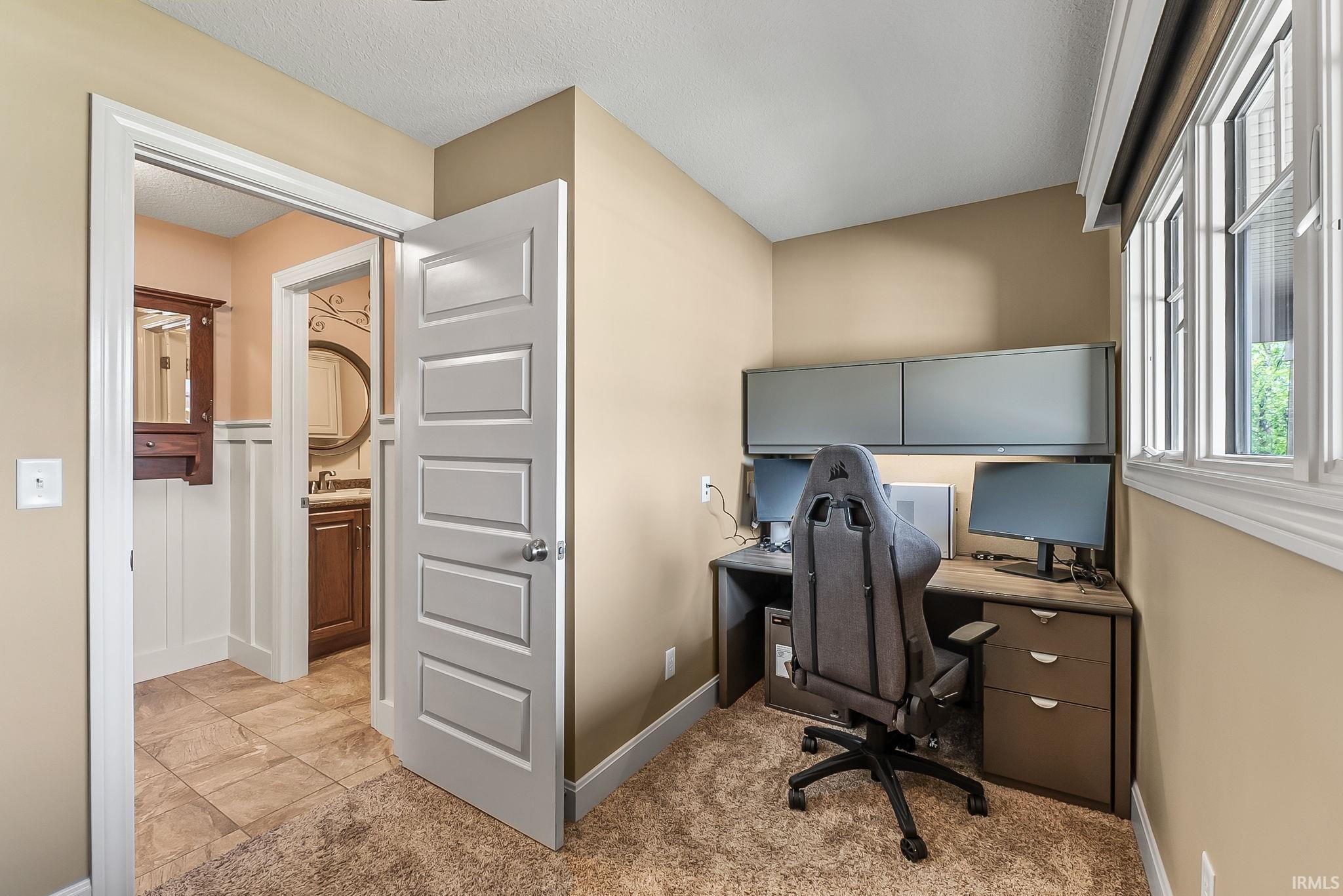 Dedicated workspace featuring built-in cabinetry, corner desk, and natural light from a multi-pane window