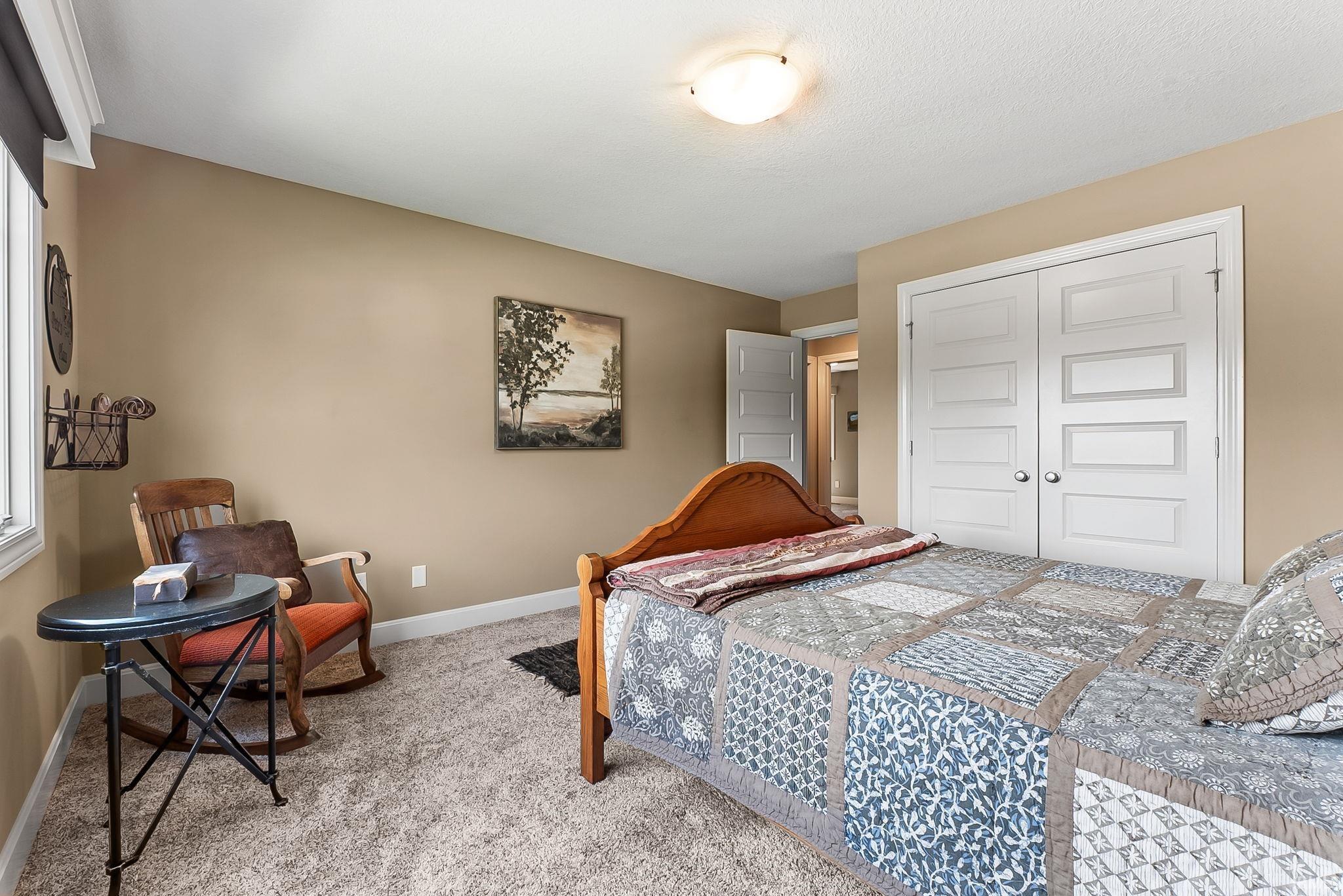 Bedroom featuring neutral paint, soft carpet flooring, white trim, and a double-door closet with panel detailing