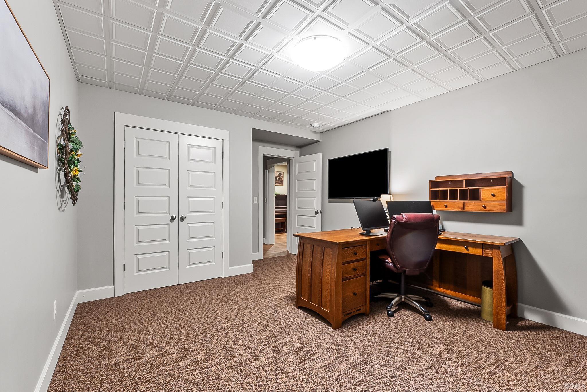 Recessed ceiling with decorative panels, light-colored walls, and textured carpeting