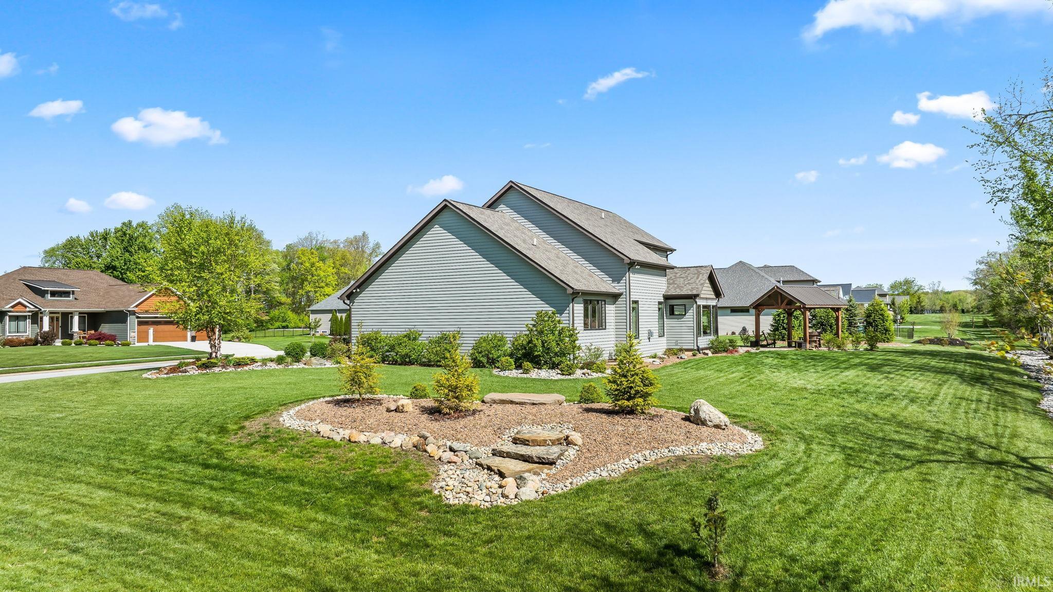Expansive manicured lawn with mature landscaping and a decorative rock border