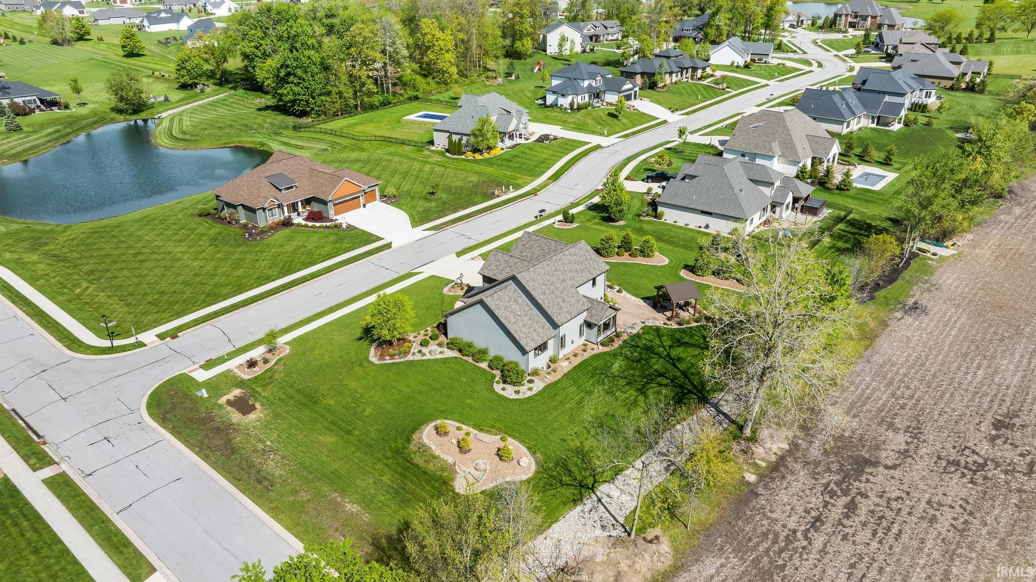 Expansive residential area featuring a central pond, paved roadways, and numerous single-family homes with diverse architectural styles