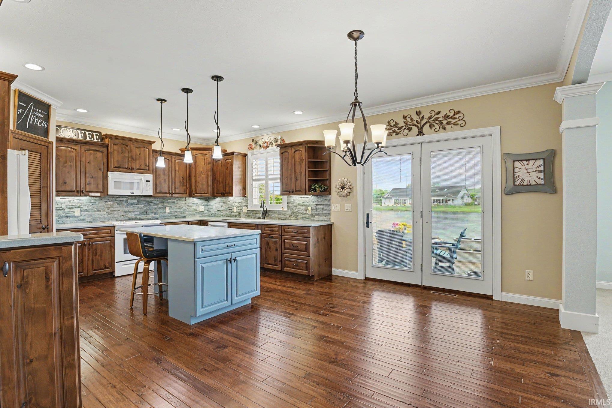 Spacious kitchen featuring rich wood cabinetry, a tiled backsplash, and a light blue island with counter seating