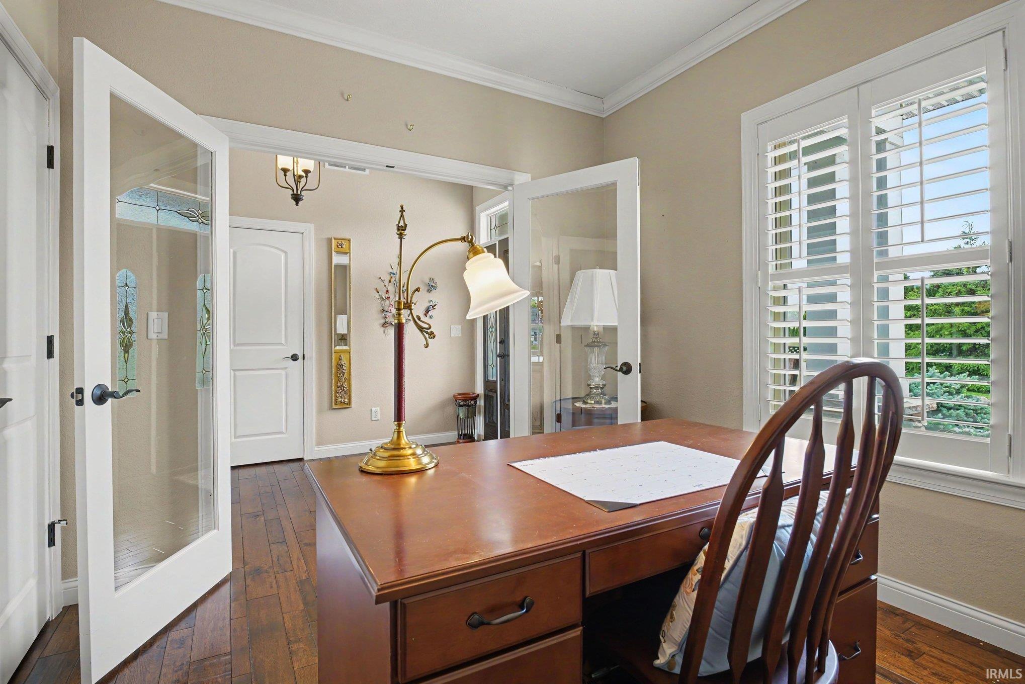 Hardwood-finish flooring extending into an inviting space with French doors and crown molding