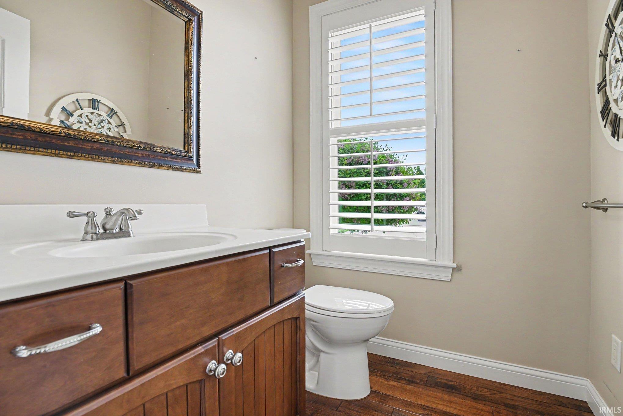 Bathroom featuring a wood-finish vanity with a white countertop and integrated sink, chrome faucet, and decorative mirror