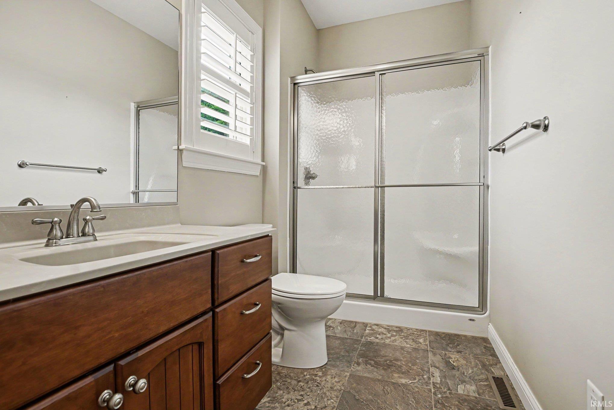 Bathroom featuring a single vanity with a light-toned countertop, wood-finish cabinetry, and a brushed nickel faucet