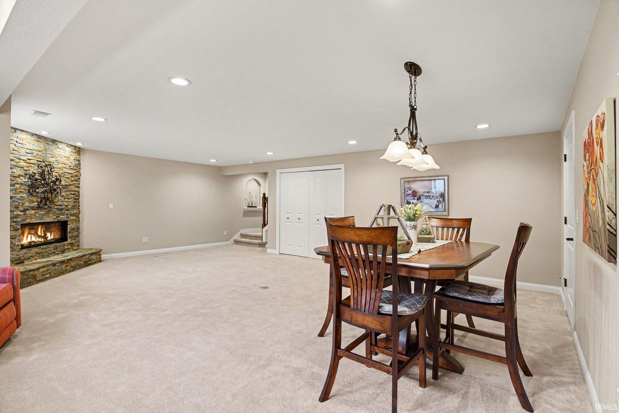 Spacious room featuring a stacked stone fireplace with an elevated hearth, recessed lighting, and light-toned wall-to-wall carpeting