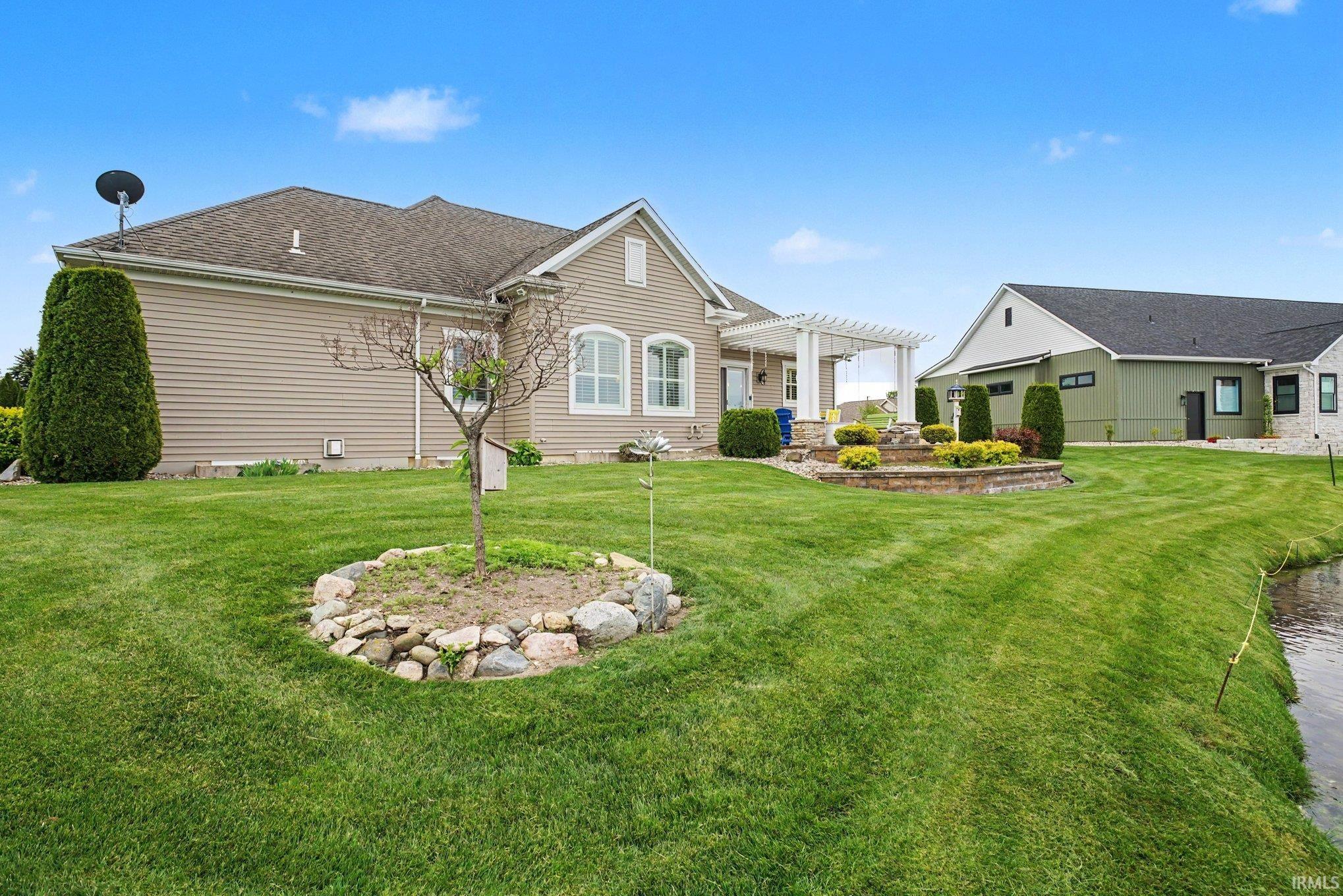 Expansive green lawn with a mature tree feature and rock border