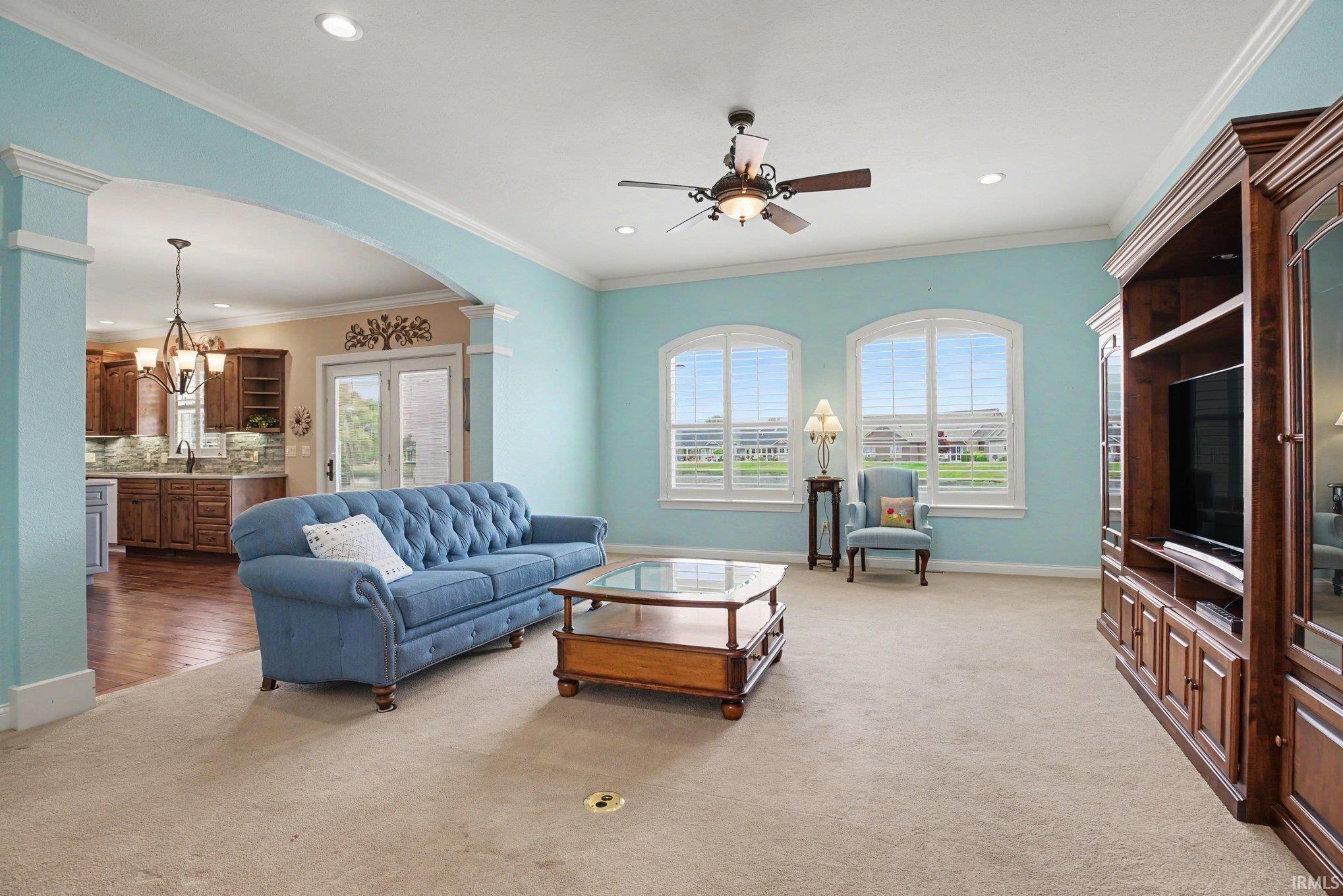 Spacious living area featuring an arched entryway, recessed lighting, and a ceiling fan
