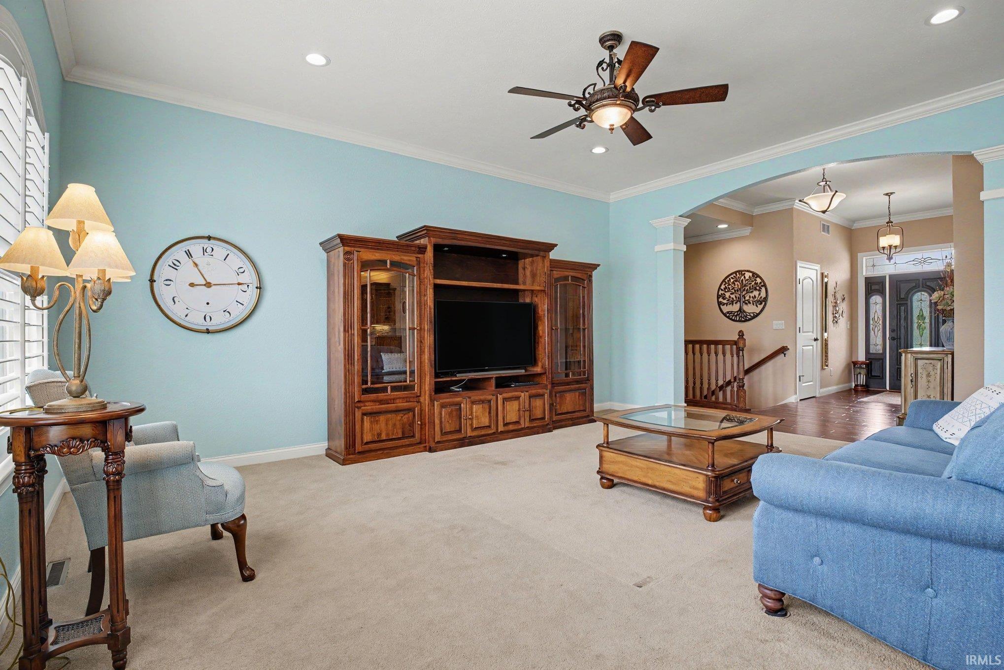 Spacious living area featuring light blue walls, recessed lighting, and a ceiling fan with integrated lighting